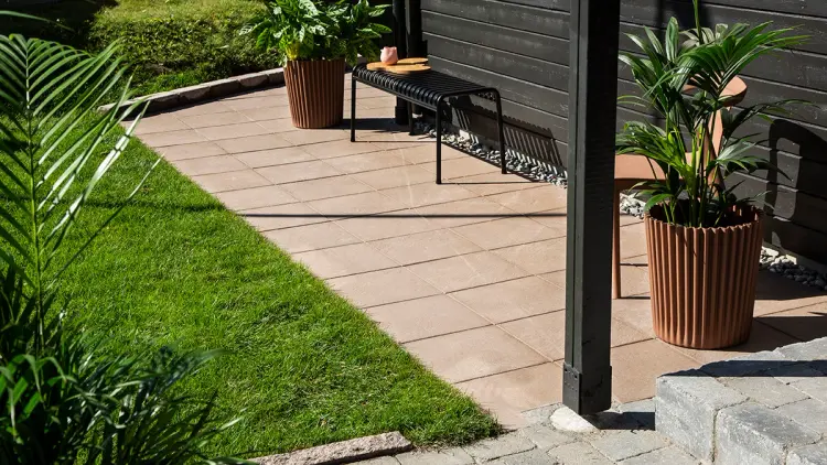 Steinheller på uteplass som er gangsti rundt svart hus.