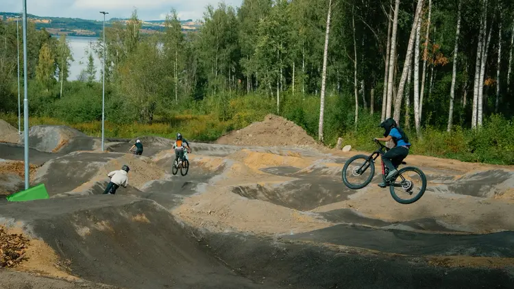 Ungdommer som hopper og sykler på hinder i en sykkelpark.