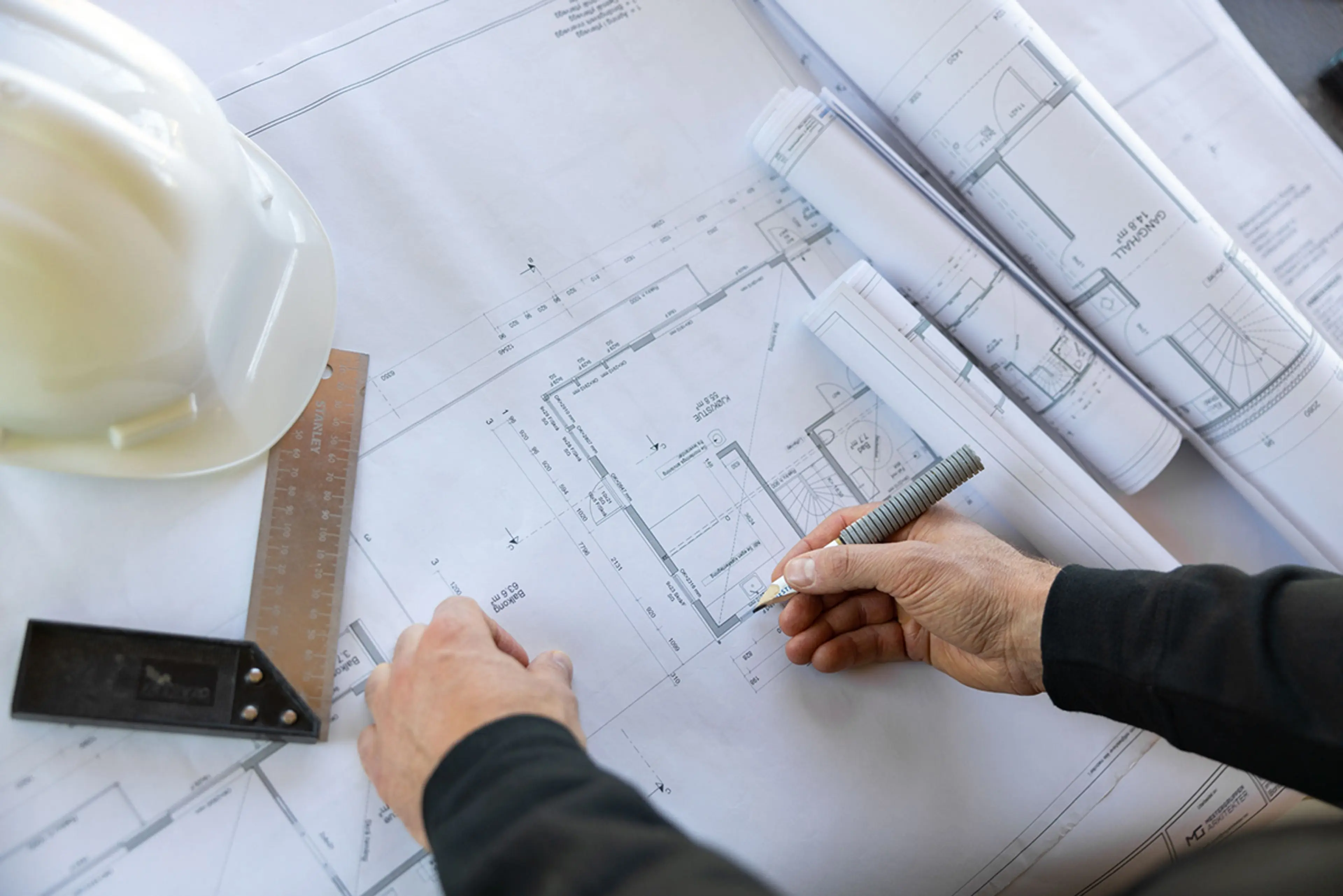 en mann ser på byggetegninger som ligger på et bord