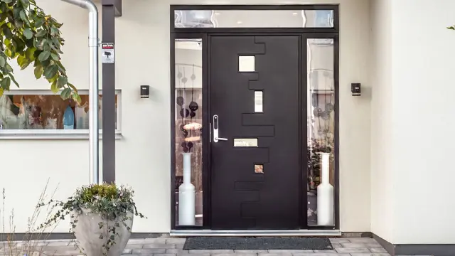 Hvitt murhus med sort inngangsdør og sidefelt i glass