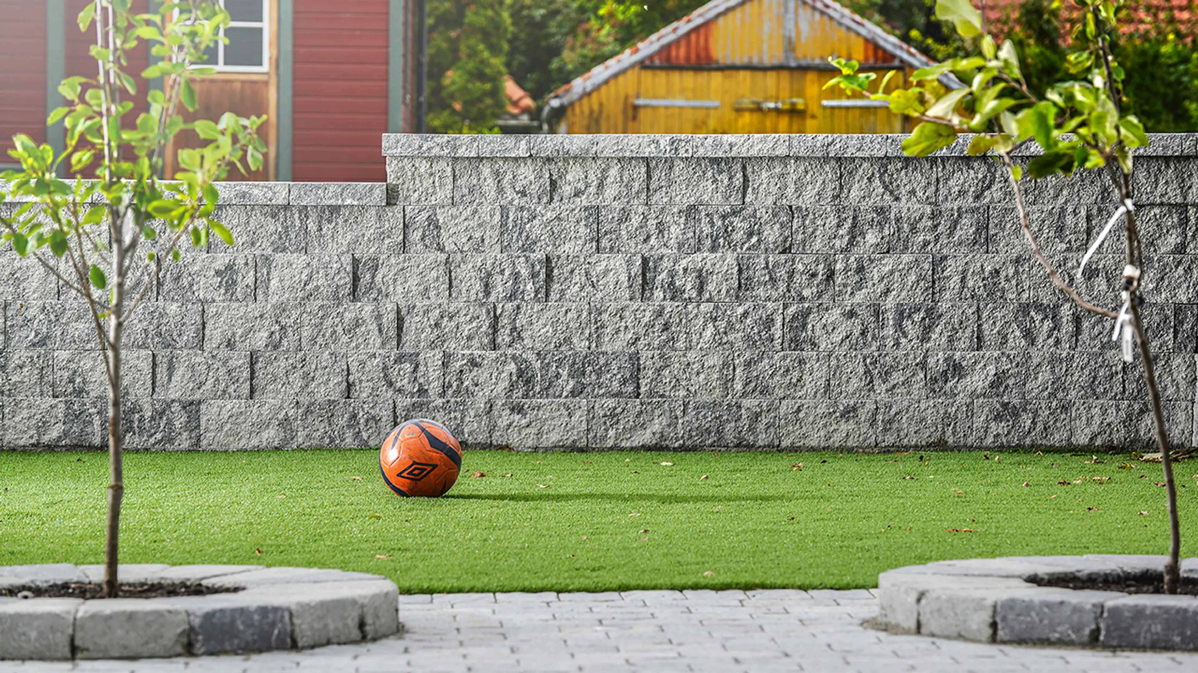 Steinmur med strukturert overflate som støttemur ved gressplen.