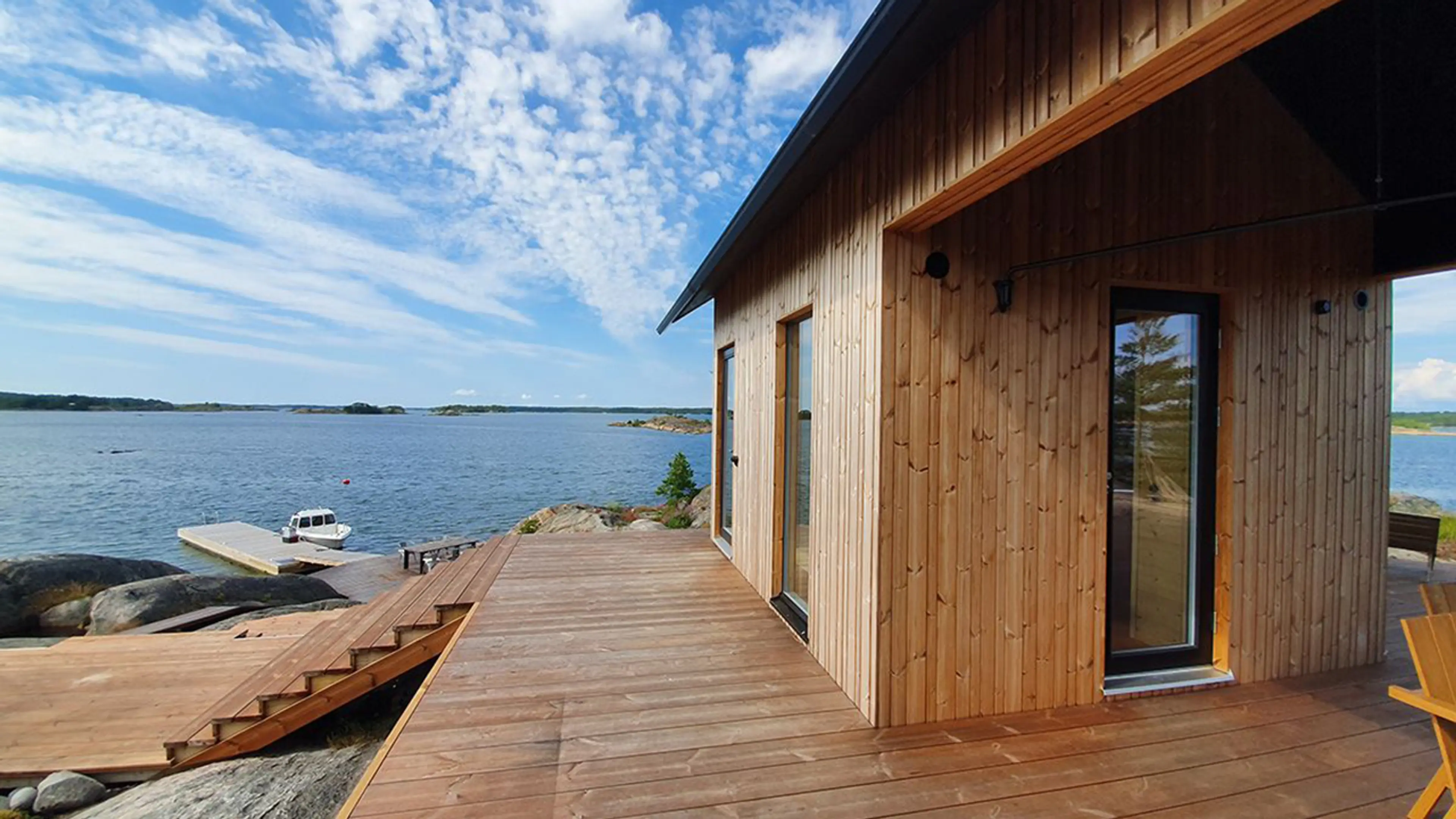 Moderne hytte i havgapet med brygge og kledning av termofuru.