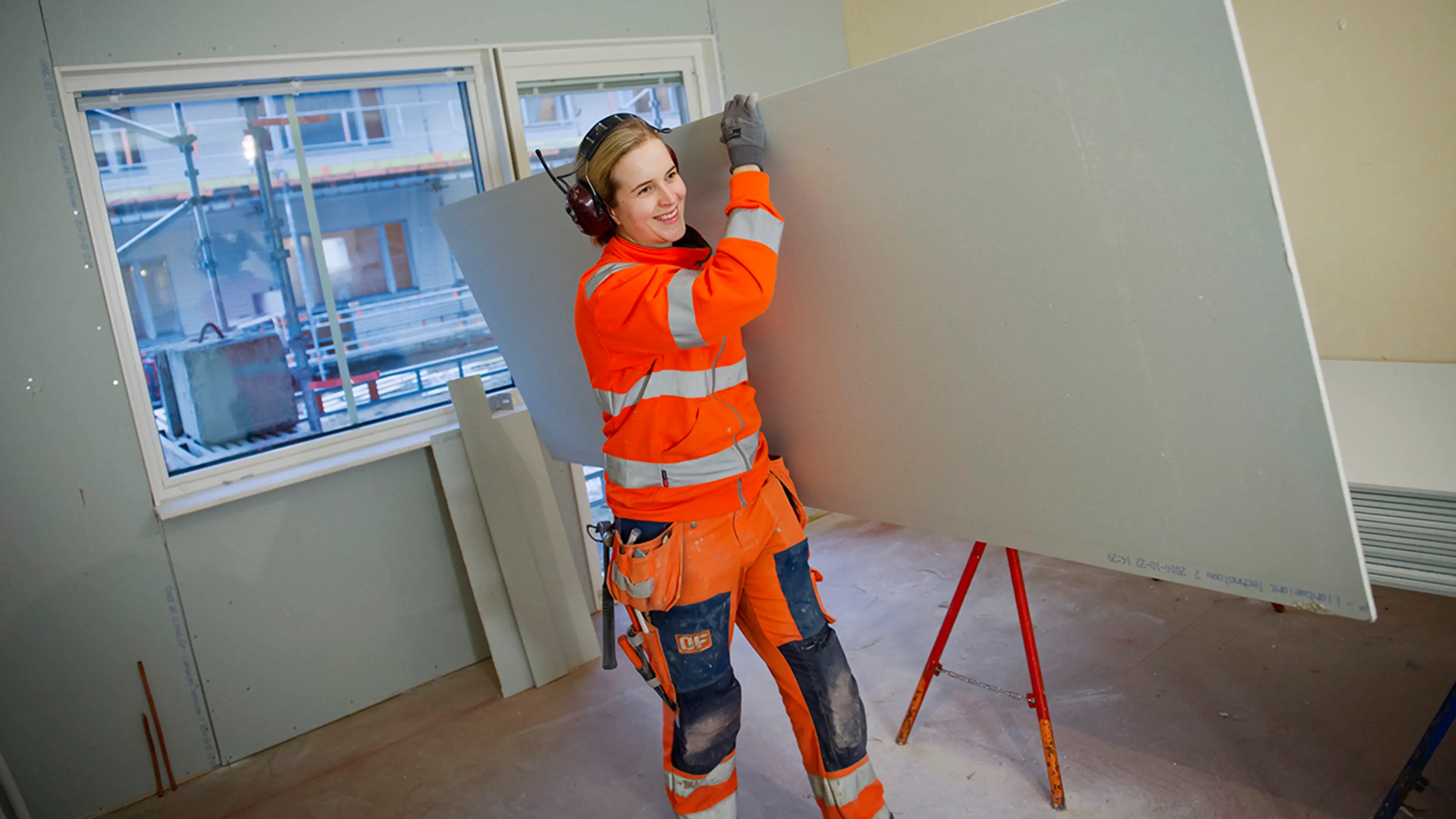 Kvinne bærer gipsplater fra Gyproc i en leilighet