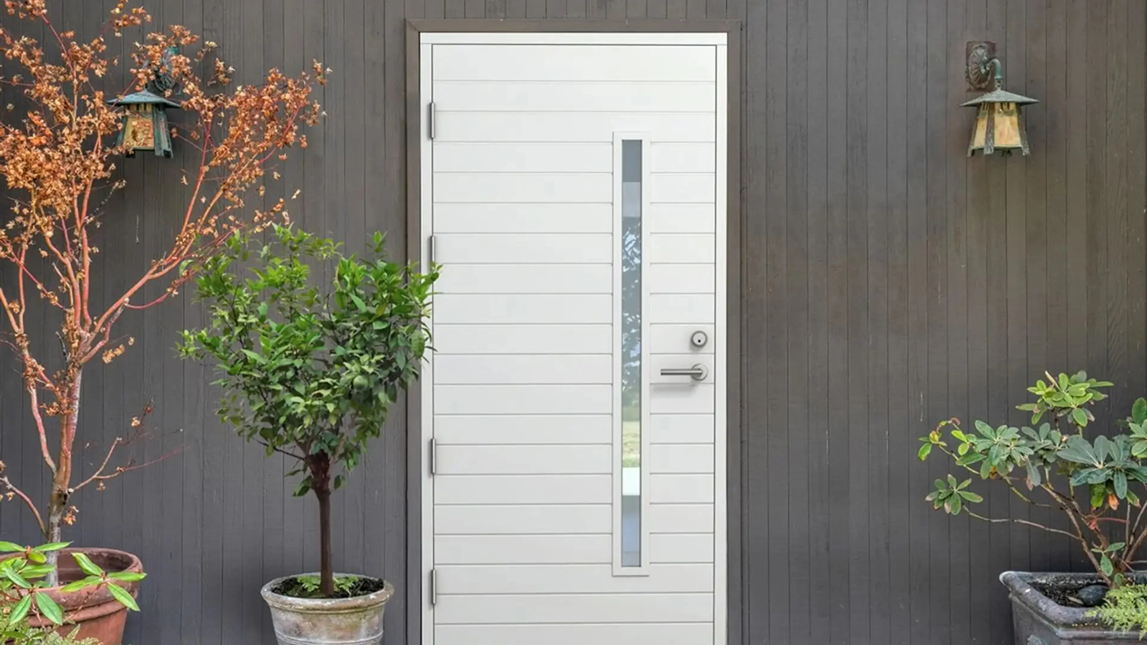 Hvit ytterdør med glassfelt på trehus med stående kledning.