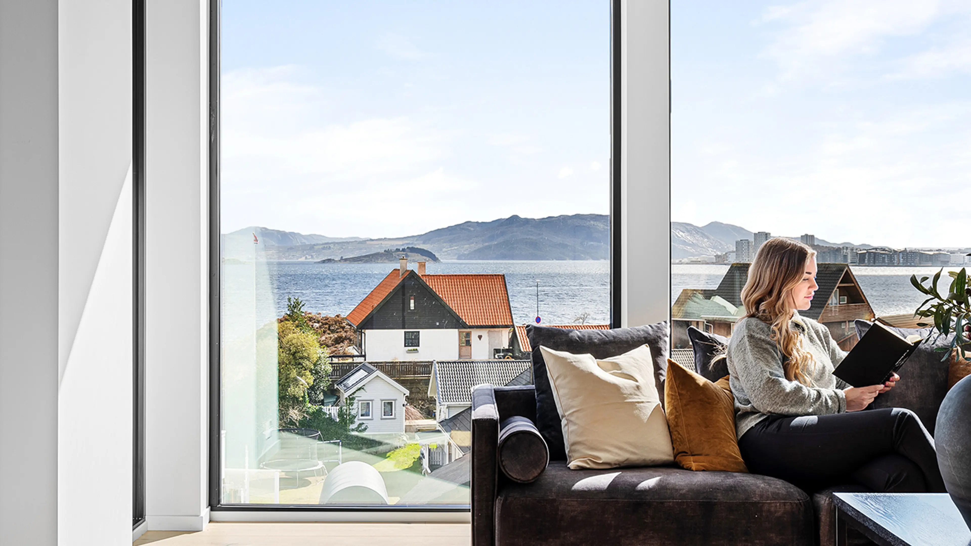 Store vindusflater med 3-lags glass i stue med en kvinne i sofaen.