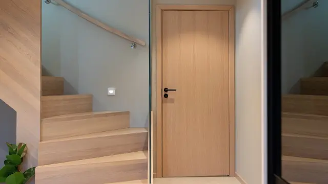 Entre med trapp og innerdør i lys eik med sorte detaljer.