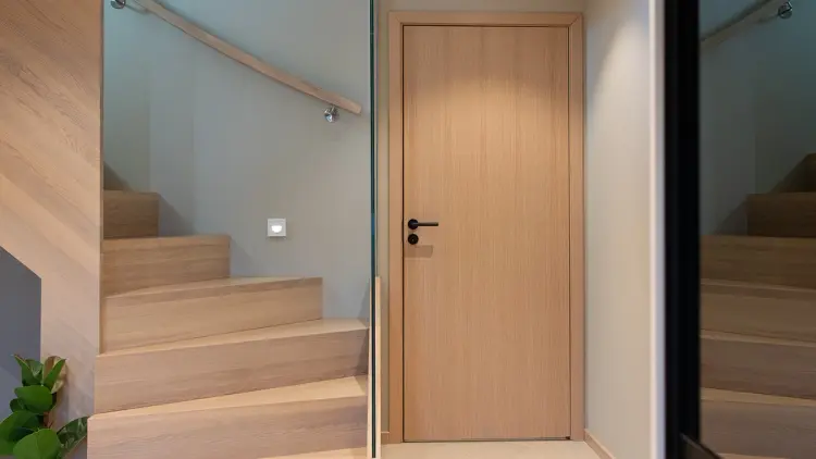 Entre med trapp og innerdør i lys eik med sorte detaljer.