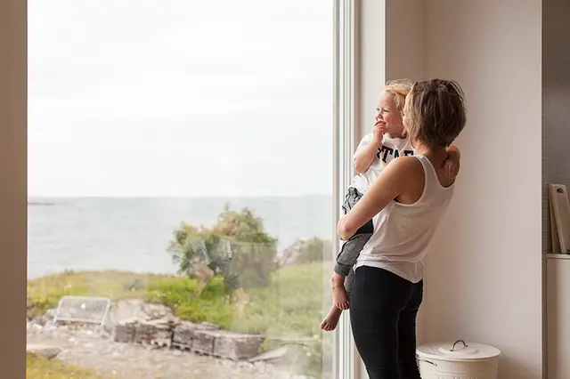 kvinne og barn ser ut av et stort vindu