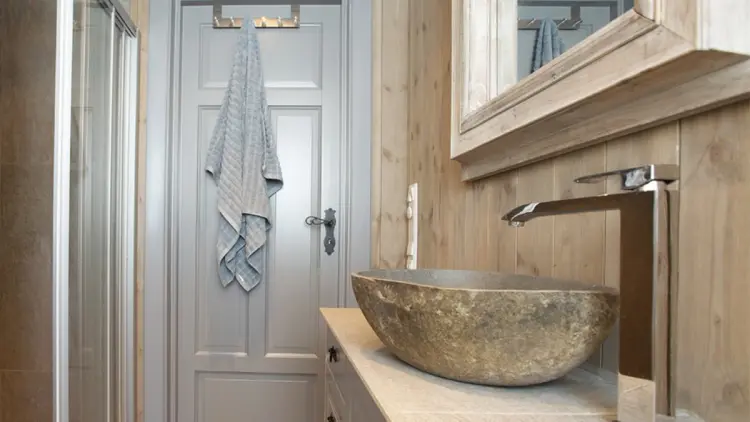 Lite hyttebad med trepanel og baderomsinnredning med steinplate.