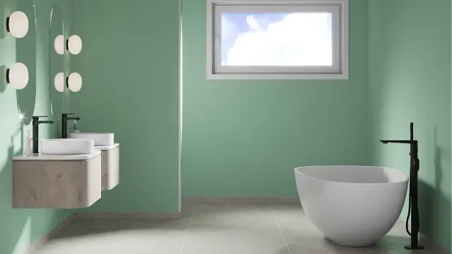 Bad med to servanter, badekar og lysegrønne veggplater.