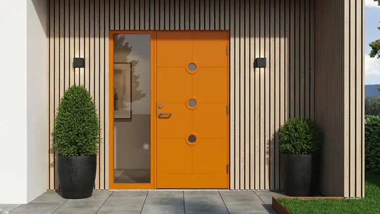 Moderne funkishus i mur med spiler og orange ytterdør med sidefelt.