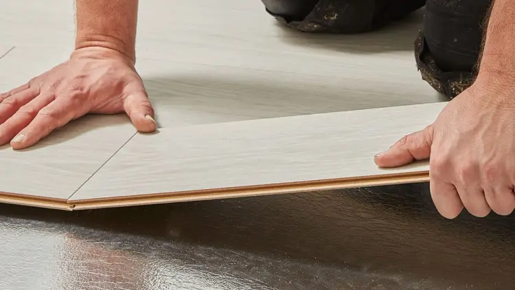 Person som holder på å legge laminat.