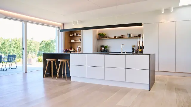 Svart og grått kjøkken med kjøkkenøy og åpen løsning.