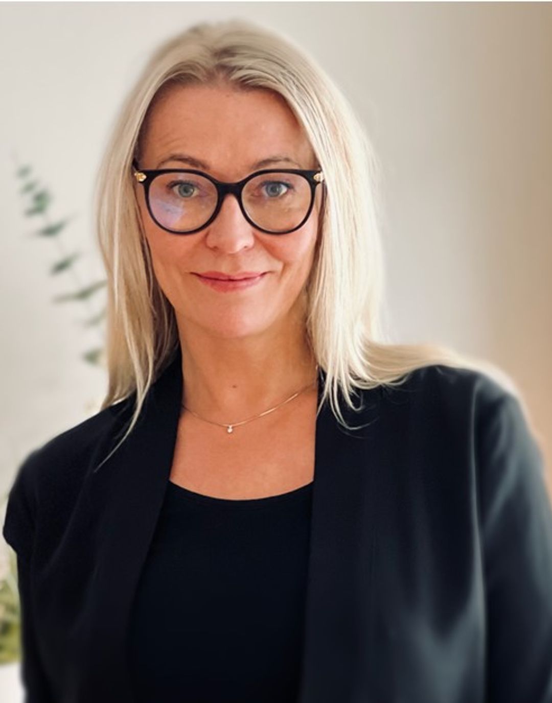 Rektor i Sonans Tønsberg, Tine Spillberg, smiler iført svarte briller og blazer mot lys bakgrunn.