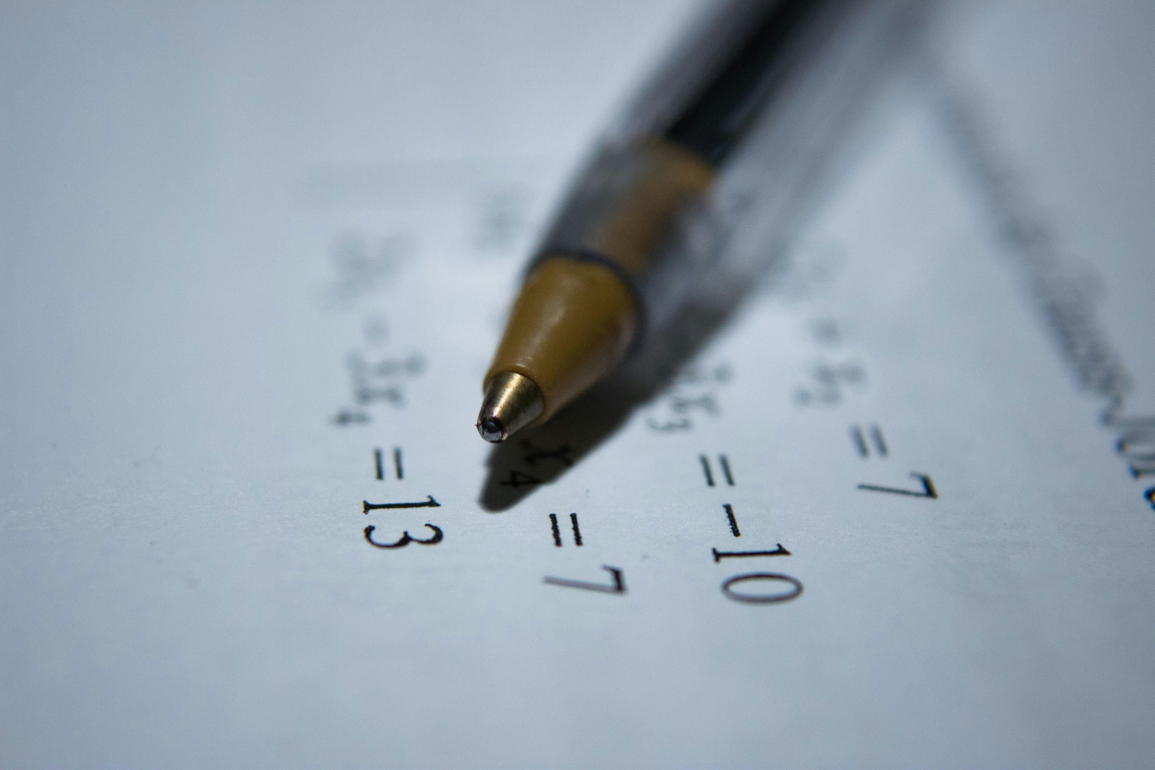 En kulepenn ligger på et ark med matematiske ligninger. Illustrasjon for matte for privatister.