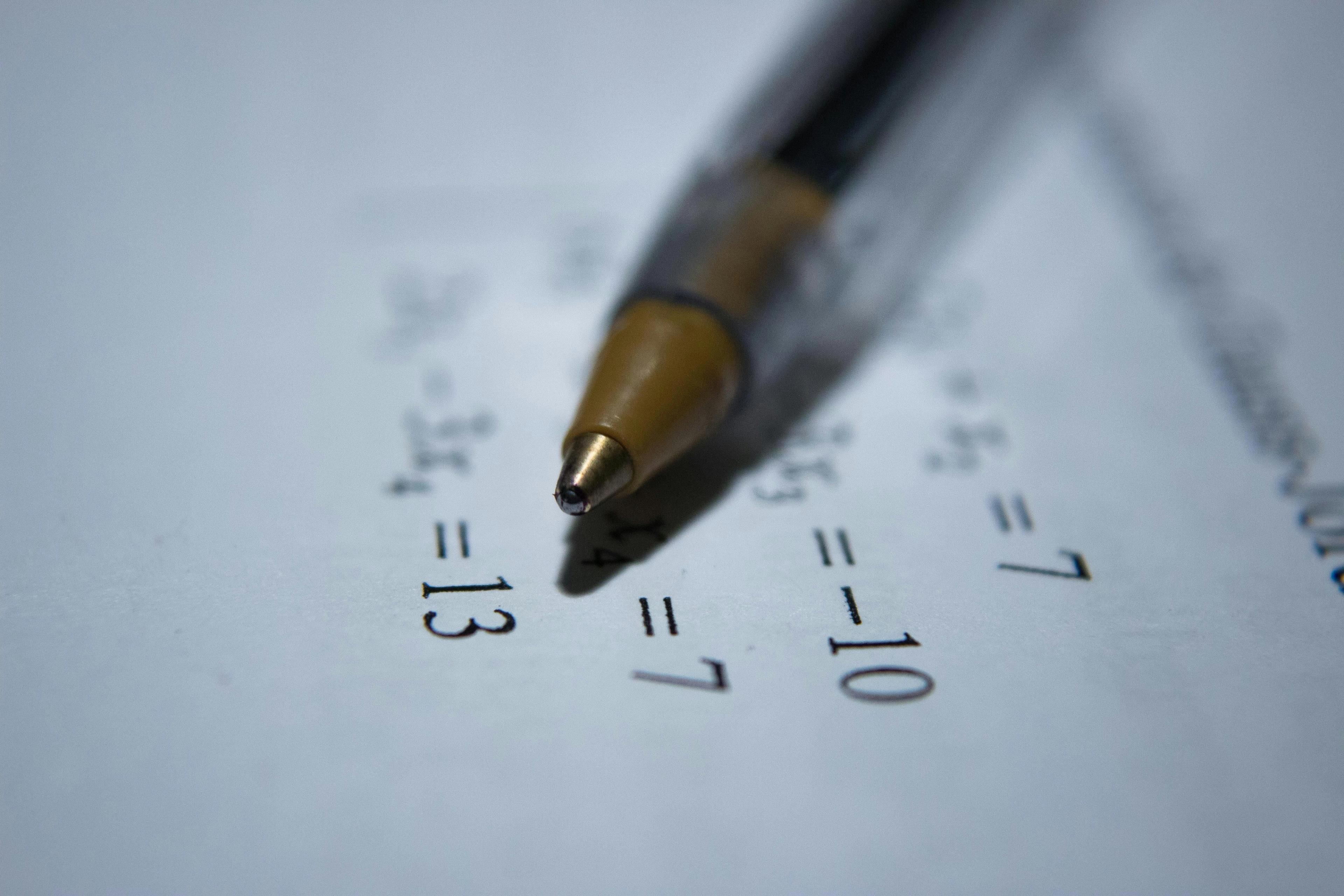 En kulepenn ligger på et ark med matematiske ligninger. Illustrasjon for matte for privatister.