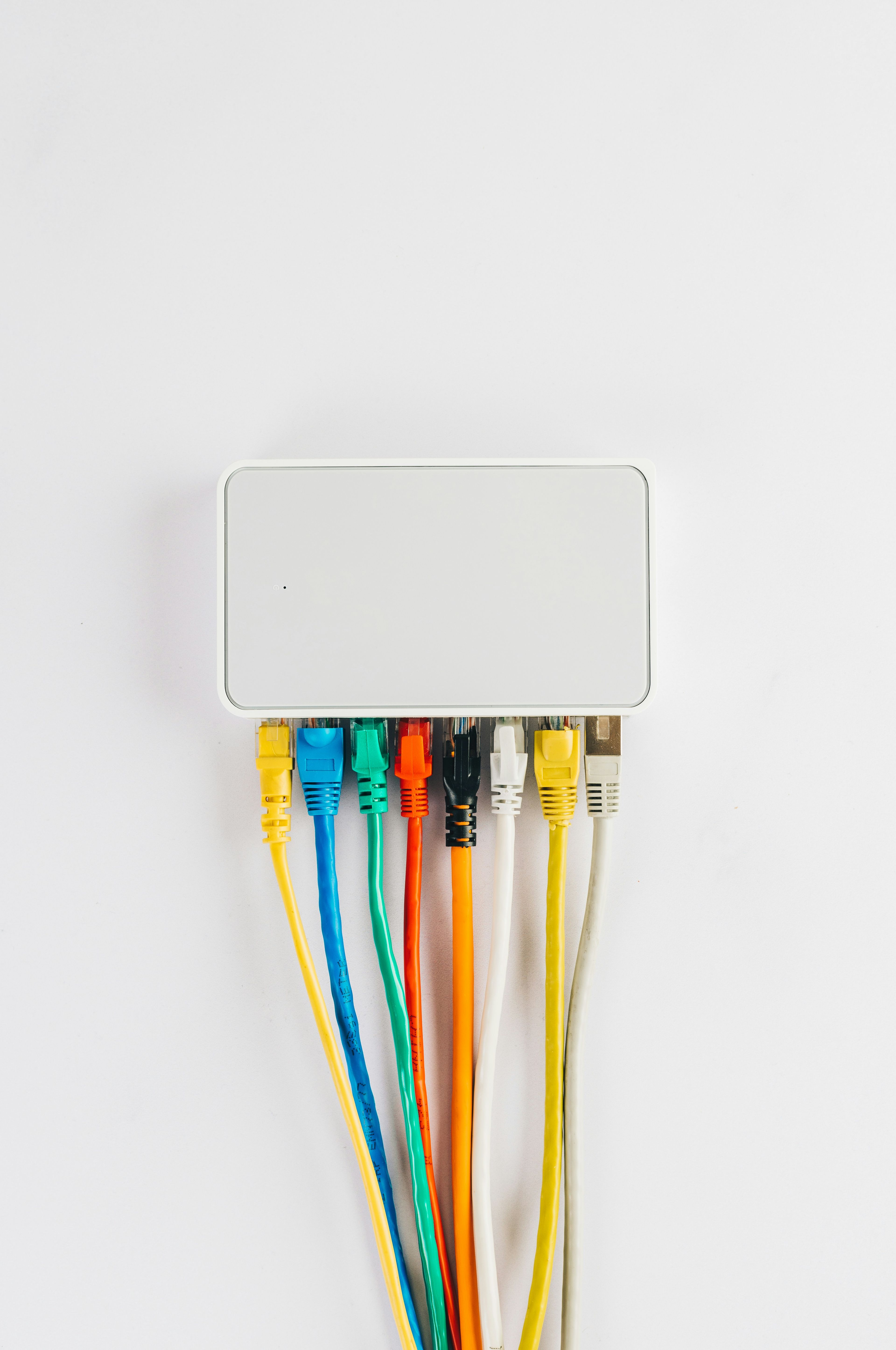 Nærbilde av en nettverksruter med flere fargerike nettverkskabler koblet til.