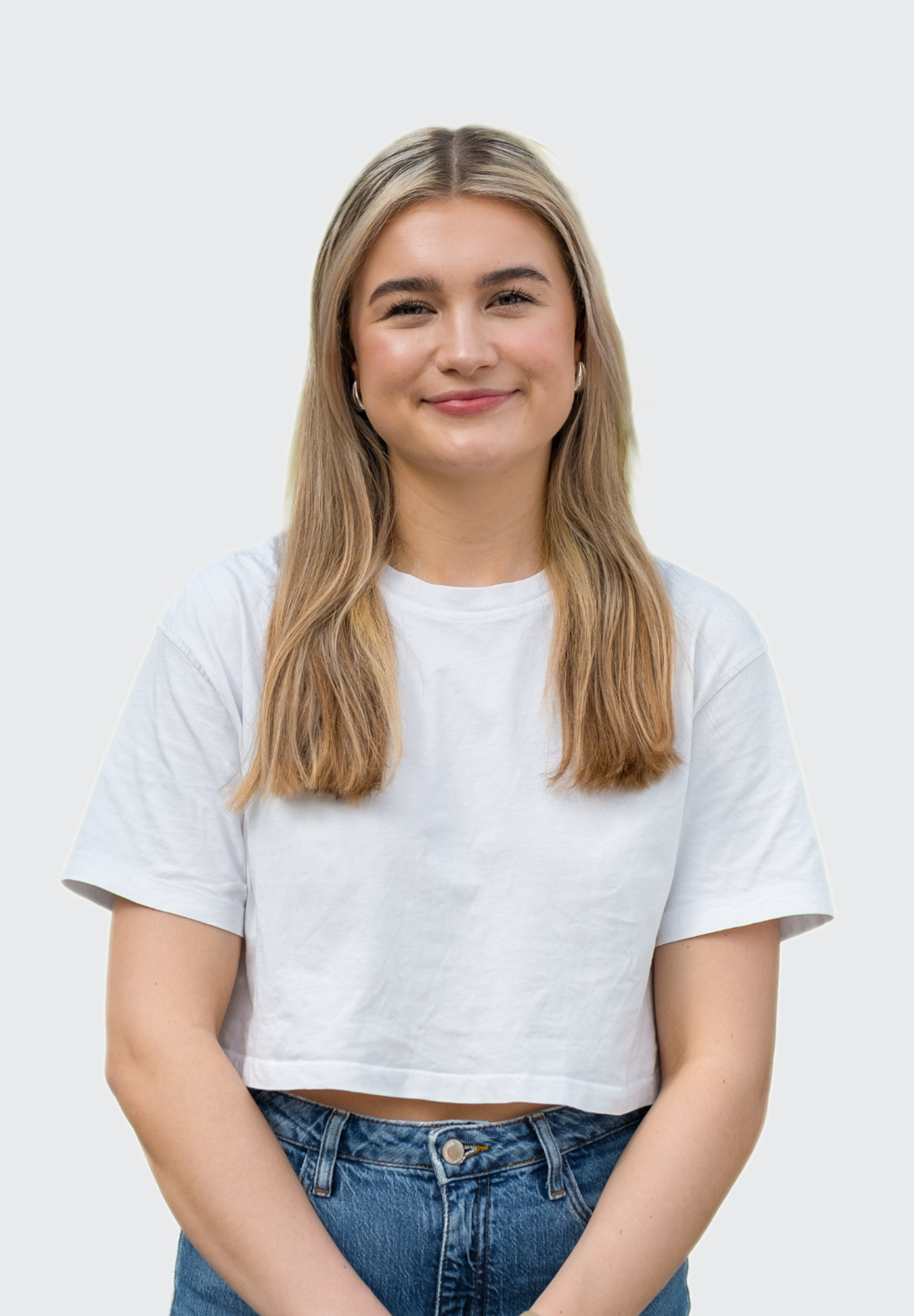 Smilende ung kvinne med langt, lyst hår i hvit t-skjorte.