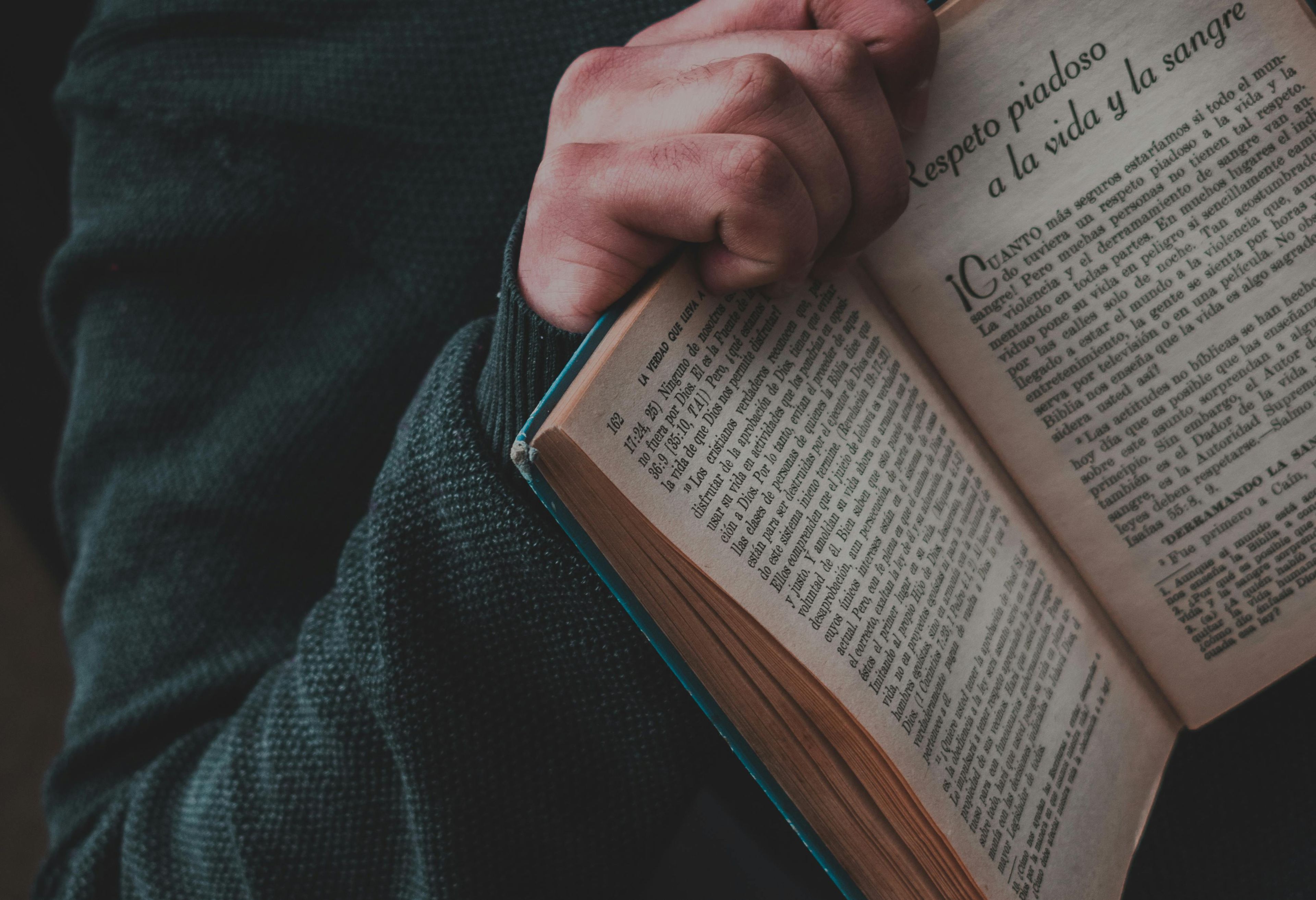 Bildet viser armen til en person som holder en skjønnlitterær bok på spansk - fordypning i språk og kultur er en viktig del av Spansk III programfag.