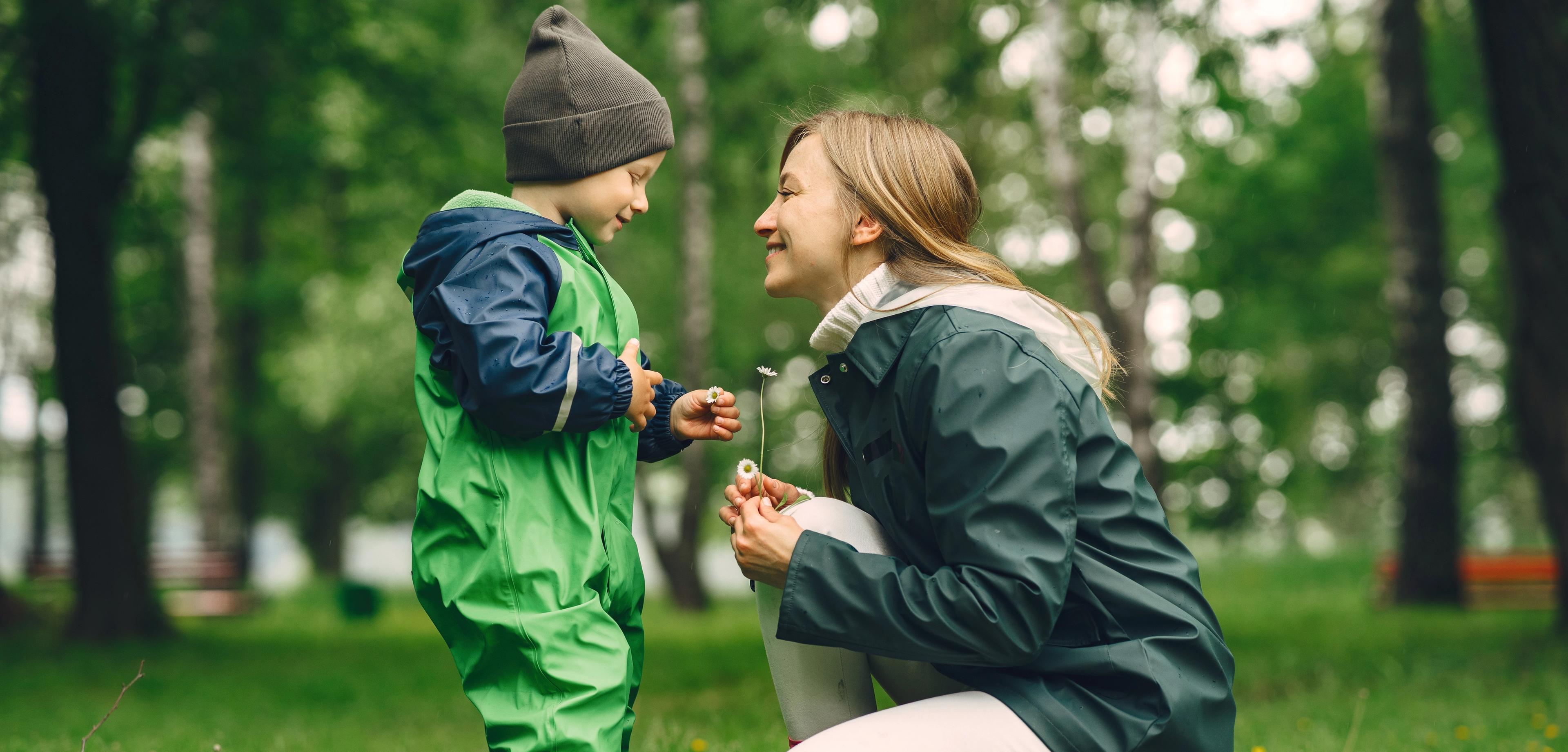 Et barn og en voksen er ute i naturen og plukker blomster -  lek og utvikling er viktig i barne- og ungdomsarbeid