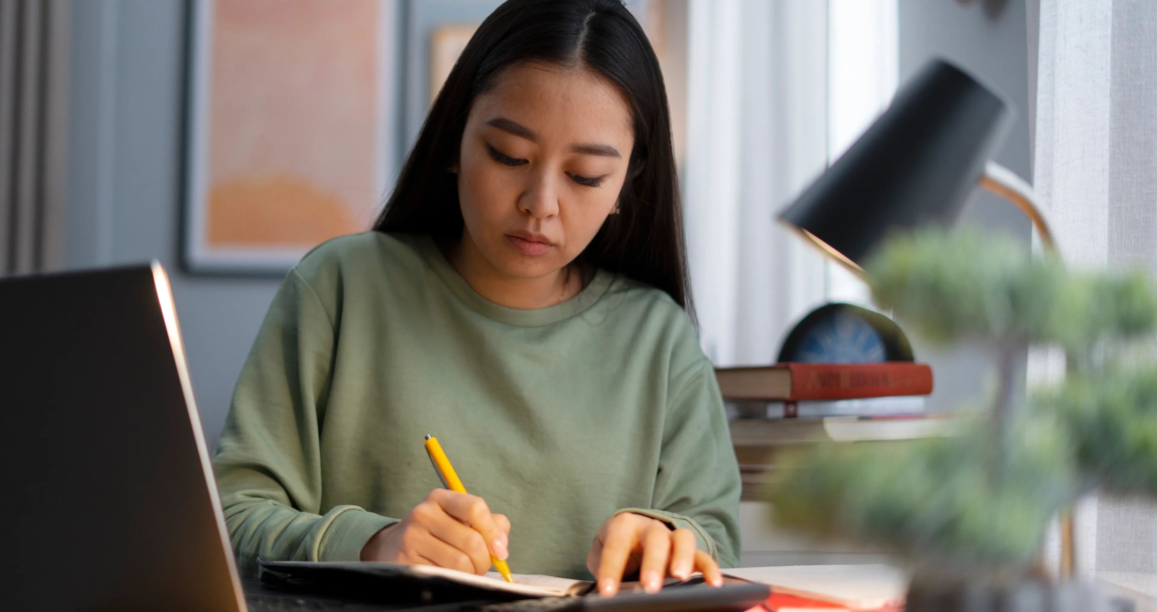 Sonans student ved et bord med notatblokk og laptop.