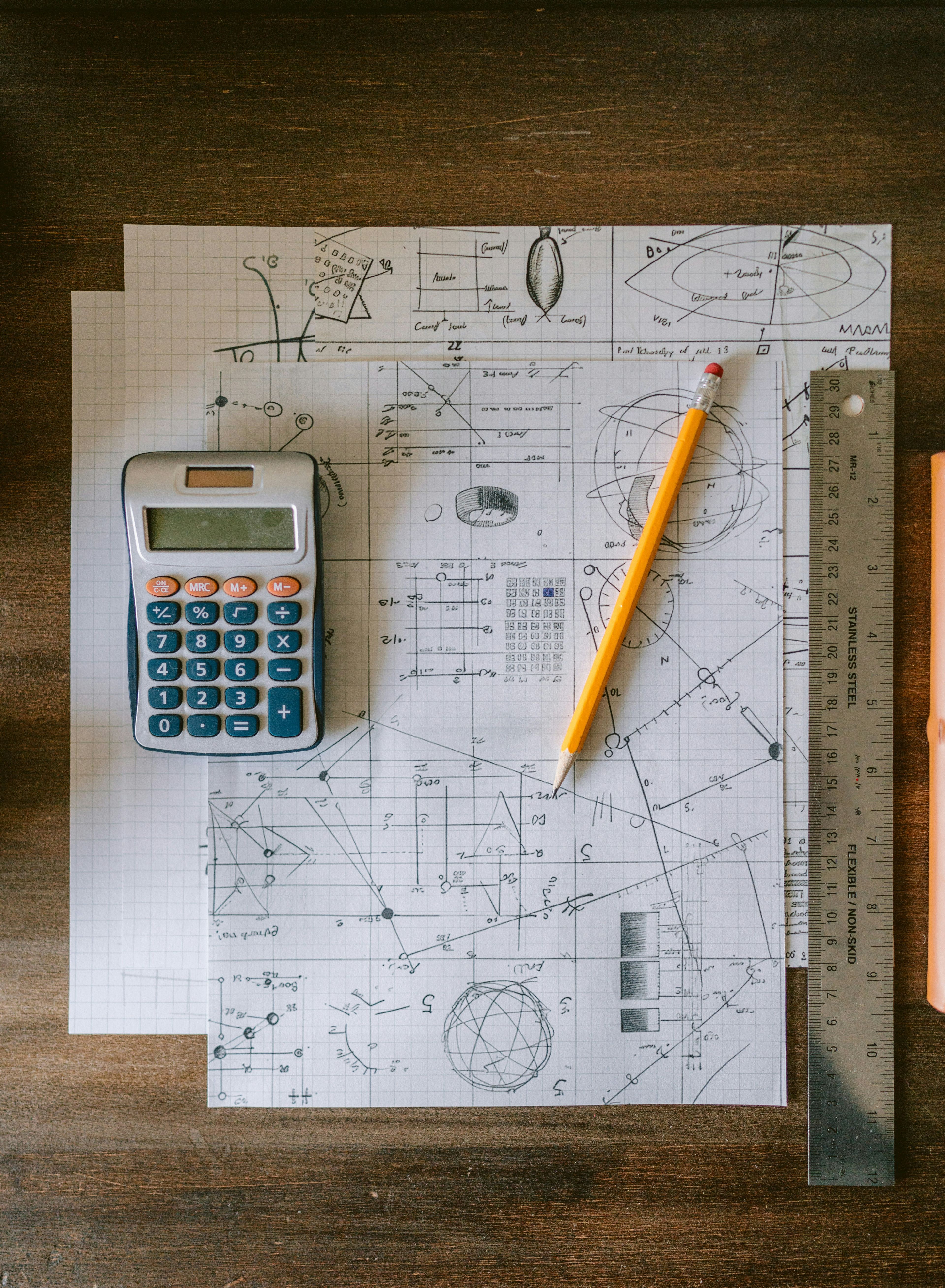 Matematiske utregninger og tegninger på rutenettark, med kalkulator og linjal - relevant for teoretisk matematikk som 1T.