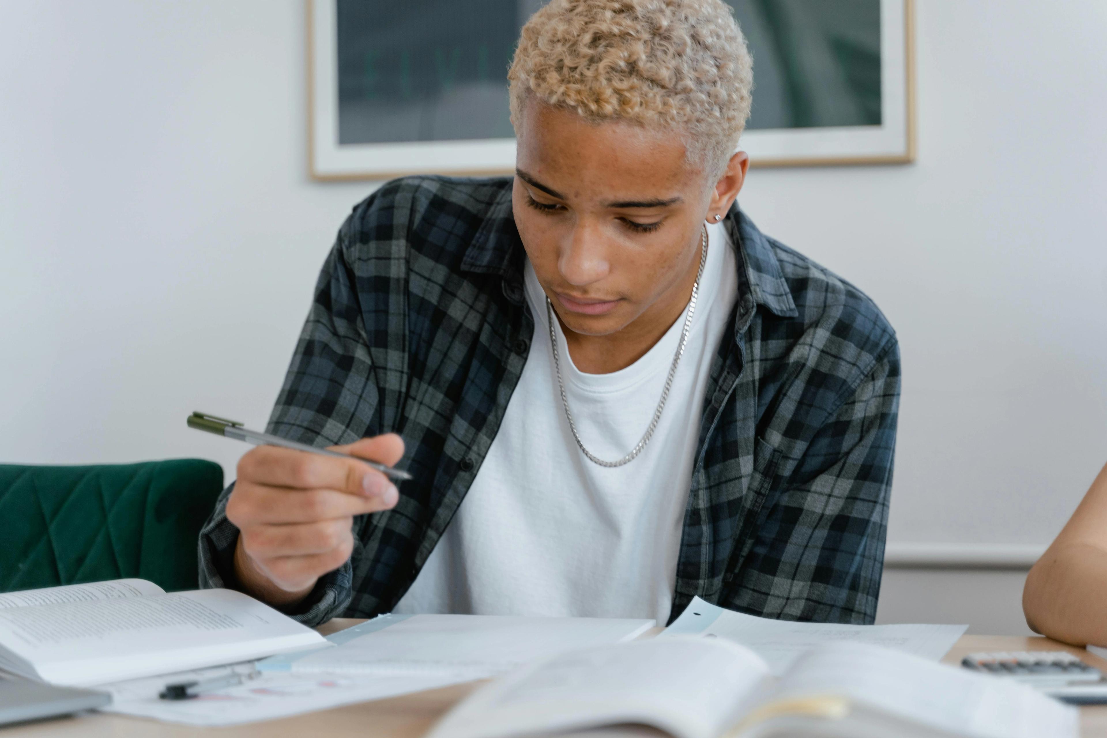 Mannlig student i rutete skjorte studerer til eksamen, for å oppnå generell studiekompetanse.