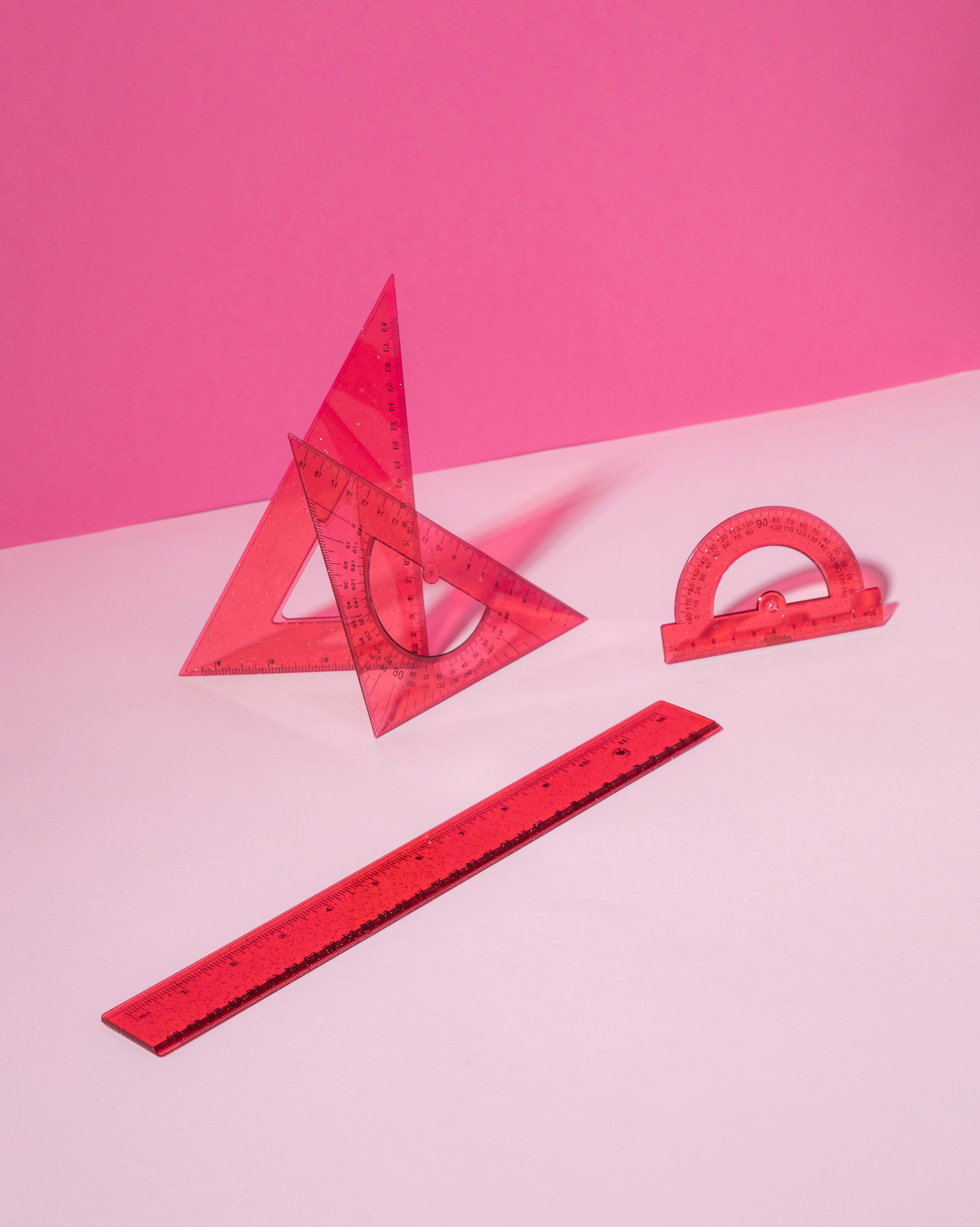 Røde linjaler på rosa bakgrunn - Verktøy som brukes i praktisk matematikk.