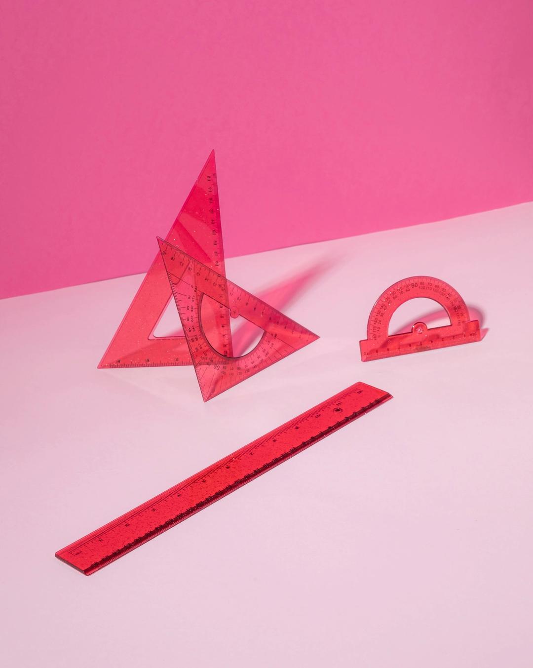 Røde linjaler på rosa bakgrunn - Verktøy som brukes i praktisk matematikk.