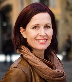 Lektor i norsk ved Sonans, smilende kvinne i bymiljø.