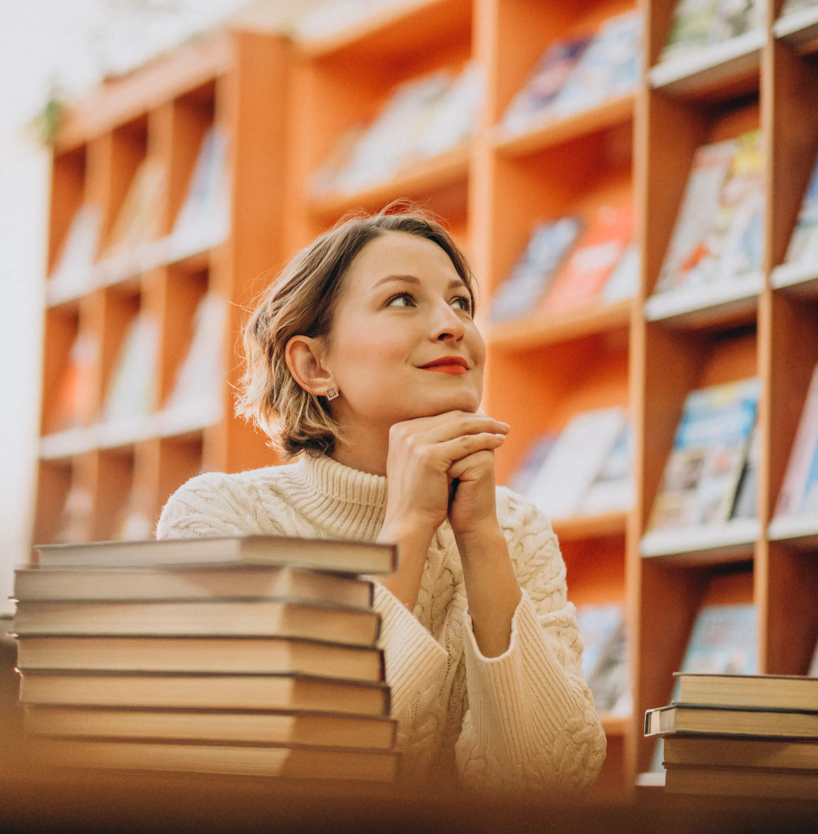 Privatist ved Sonans sitter ved et bord i biblioteket med stabler av bøker foran seg. Hun ser opp og hviler hendene under haken.