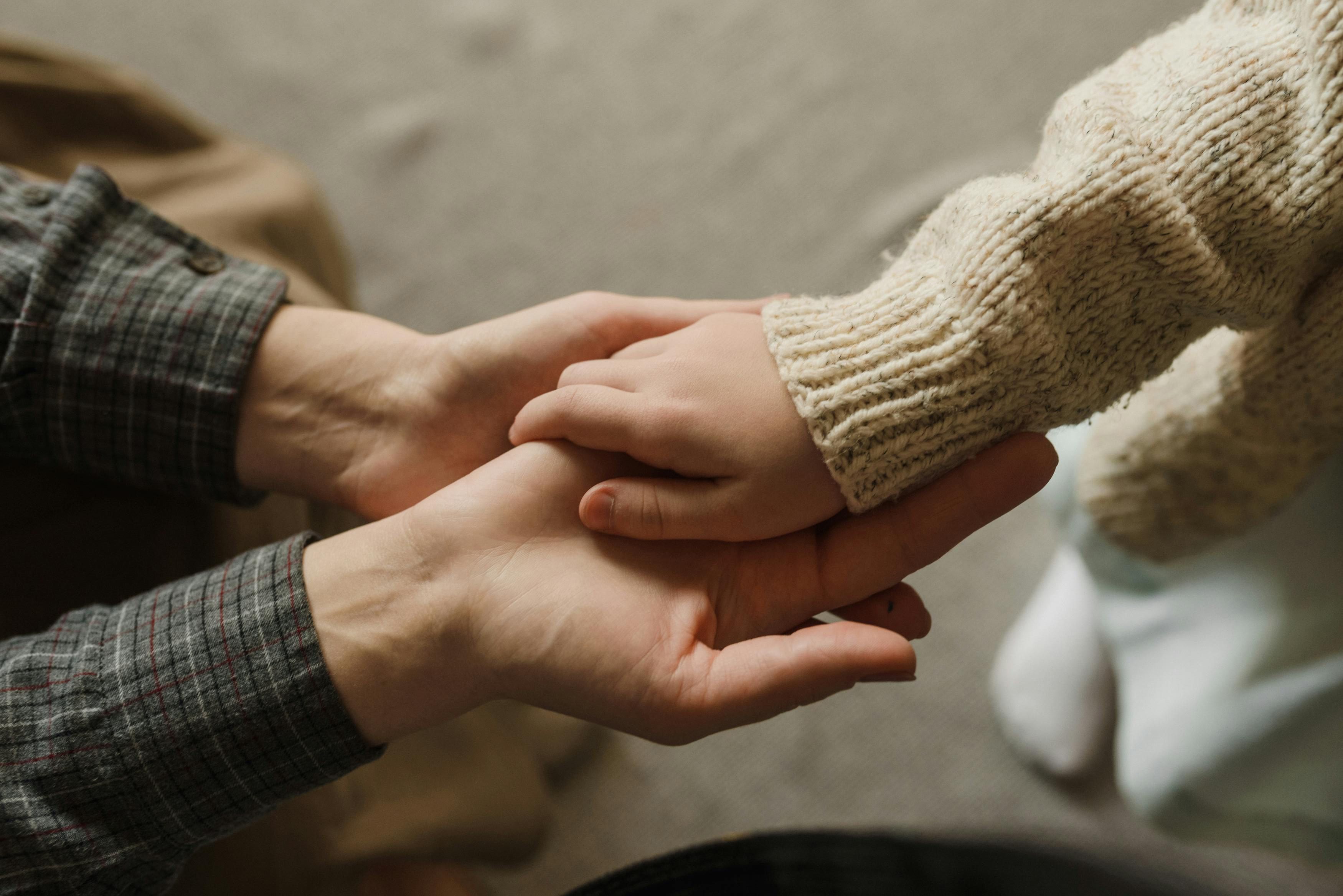 Bilde av en barnehånd som holder på hånden til en voksen.