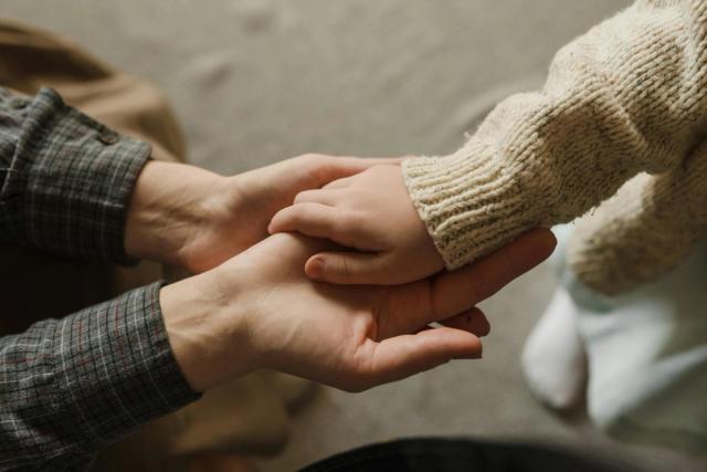 Bilde av en barnehånd som holder på hånden til en voksen.