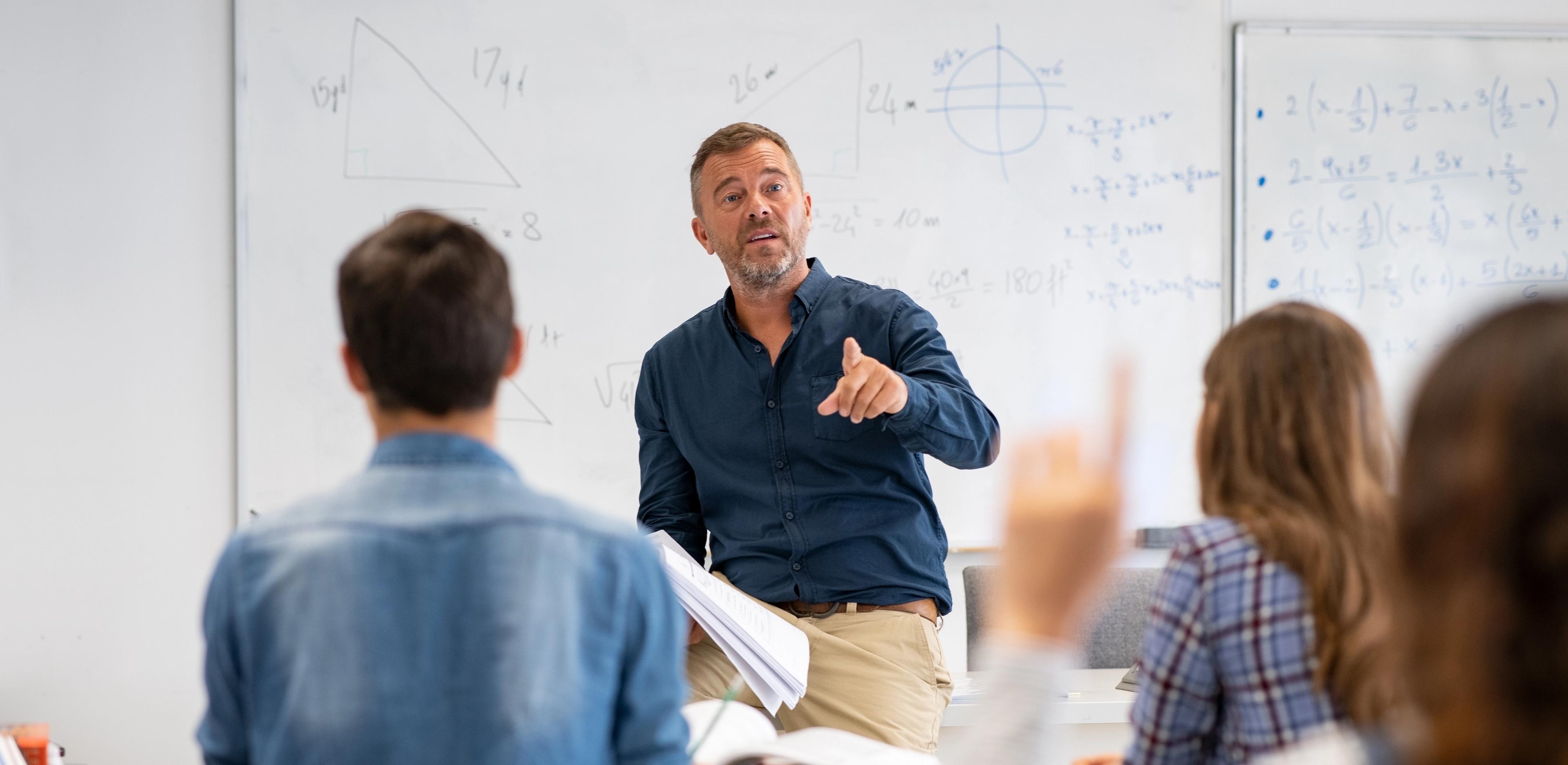 En lærer står foran en klasse og underviser i matematikk på Sonans.