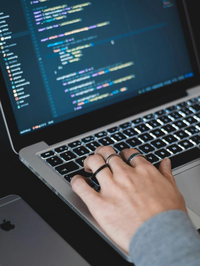 En person koder på en laptop, programmering er sentralt tema i Informasjonsteknologi 1.