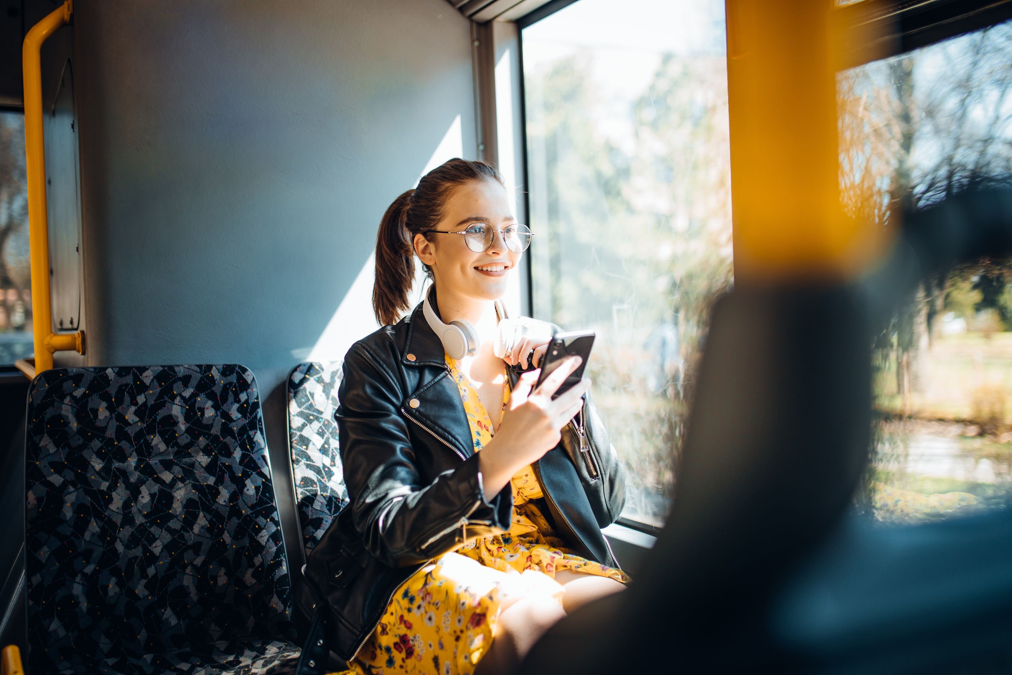 Student med hodetelefoner og mobil nyter bussturen etter å ha kjøpt billett med studentrabatt.