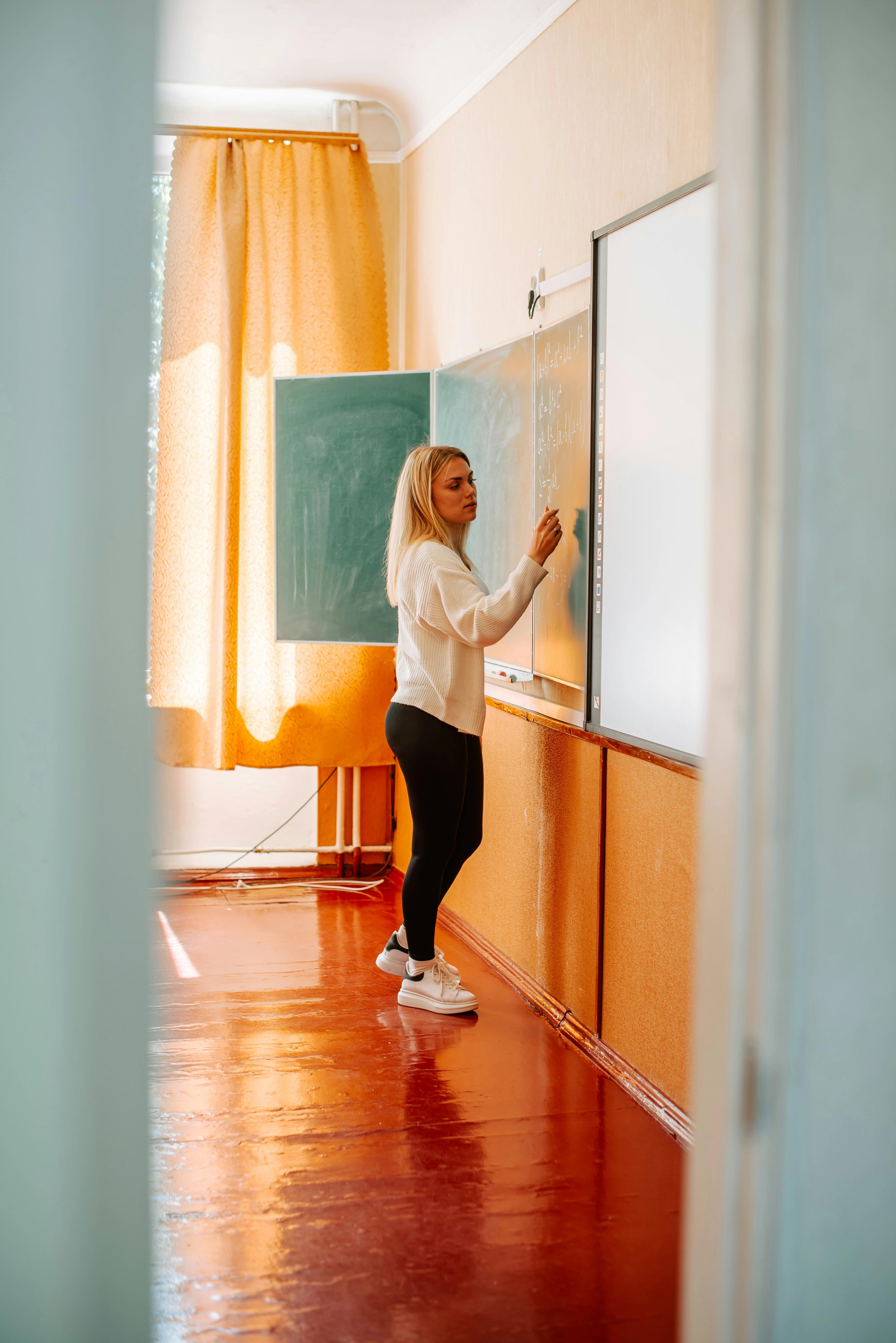 Lærer skriver på tavle i klasserom.