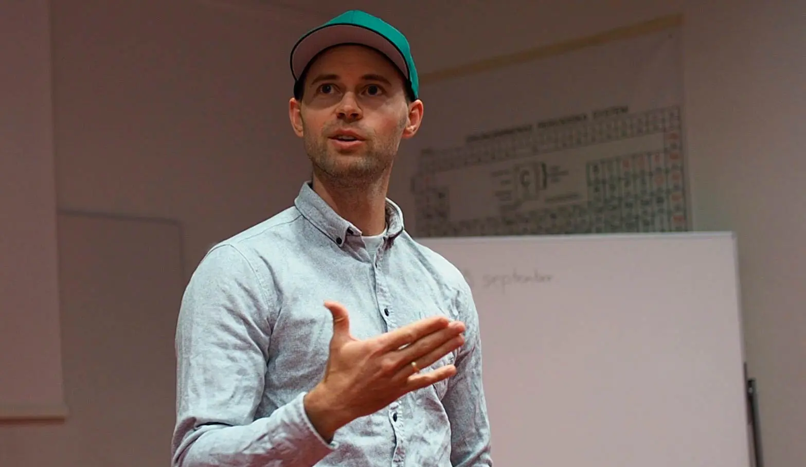 Oddbjørn By gir eksamenstips i klasserom, foran tavle med periodesystemet i bakgrunnen.