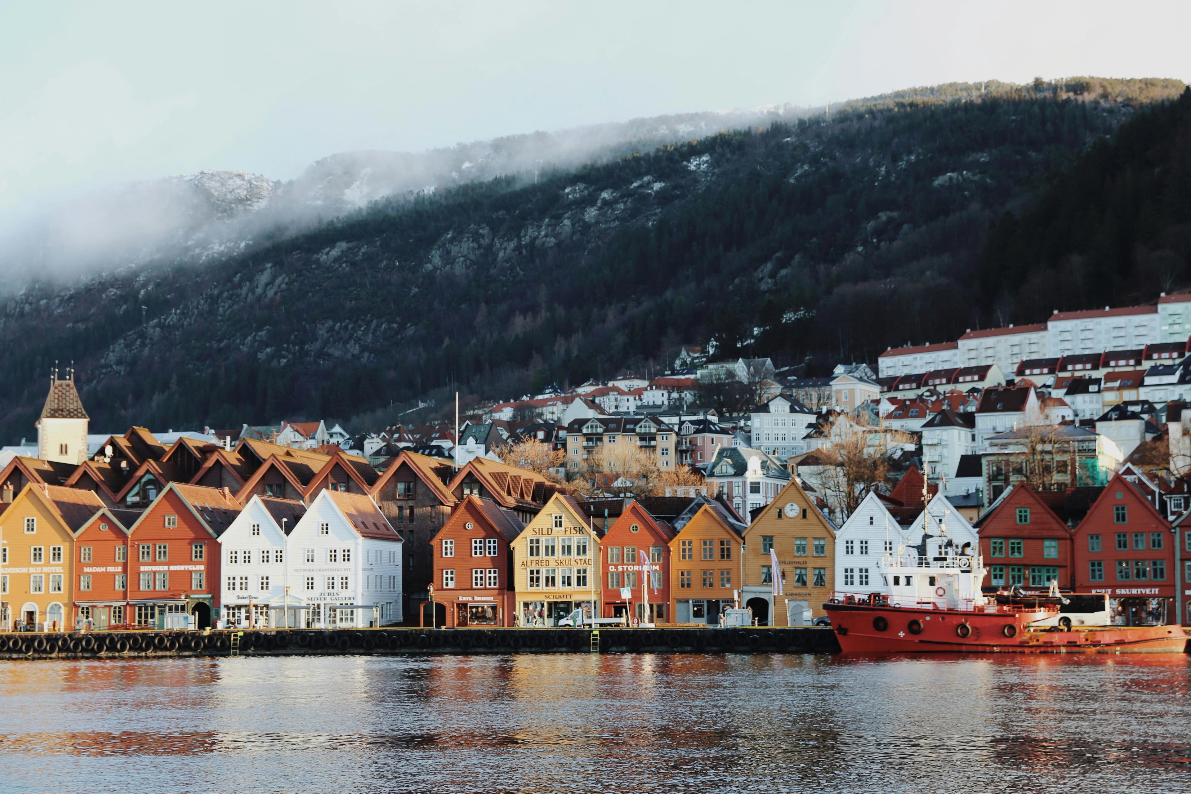 Bryggen i Bergen med fargerike trehus langs vannet og fjell i bakgrunnen.