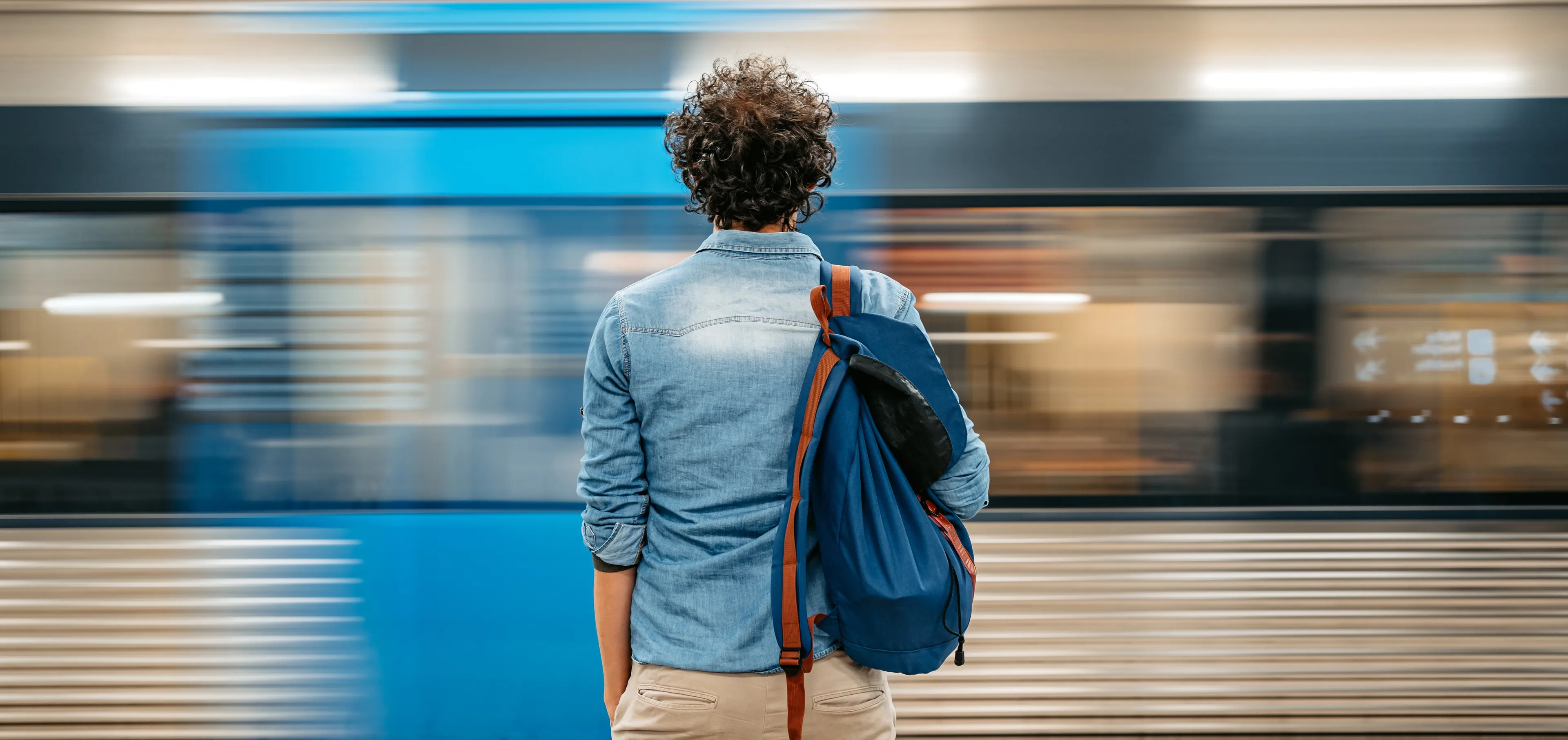 Student står på perrongen og ser trikken kjøre forbi.