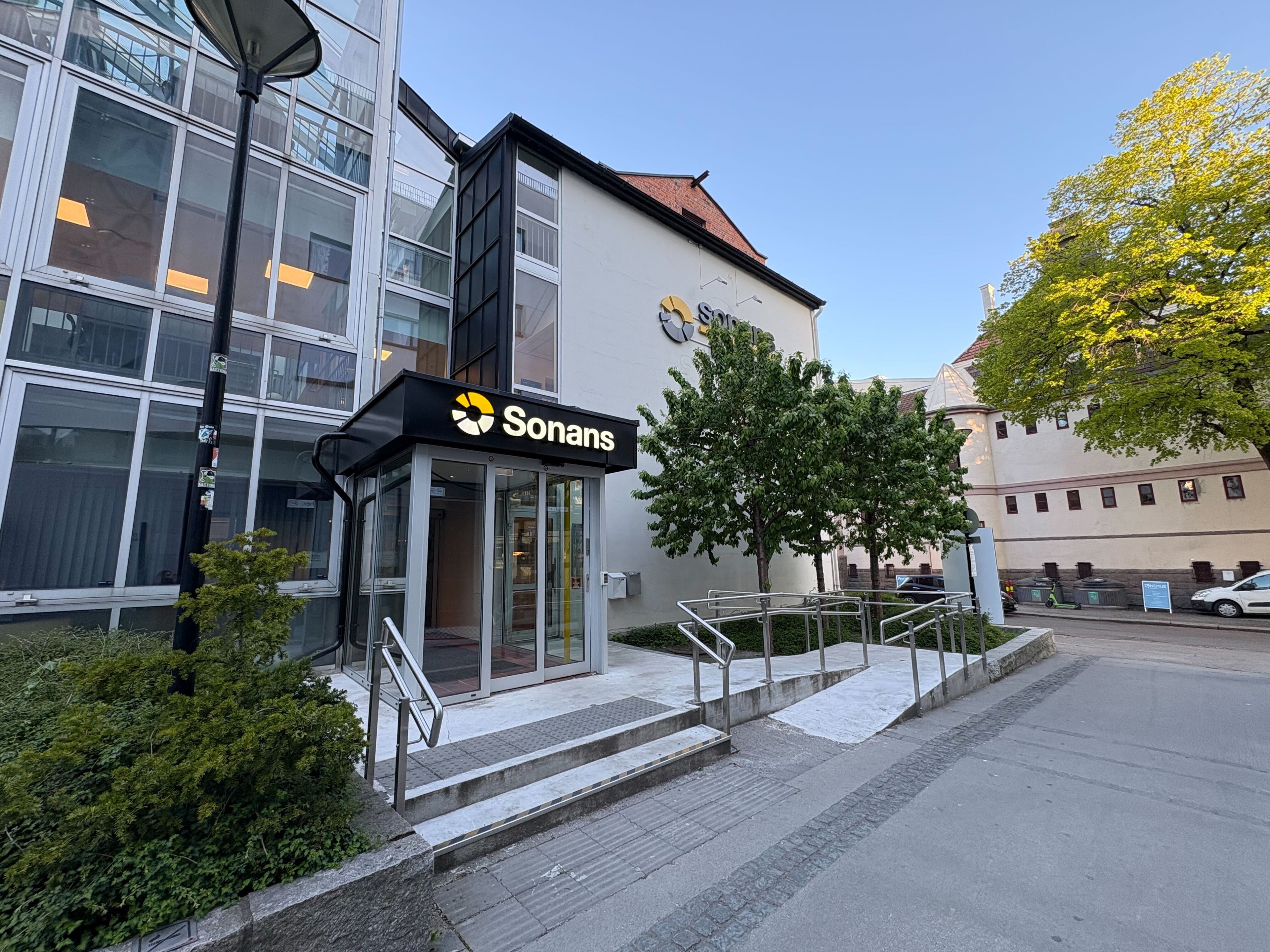 Sonans Utdanning-bygningen på Bislett, med parkeringsplasser, trær og bymiljø i bakgrunnen.