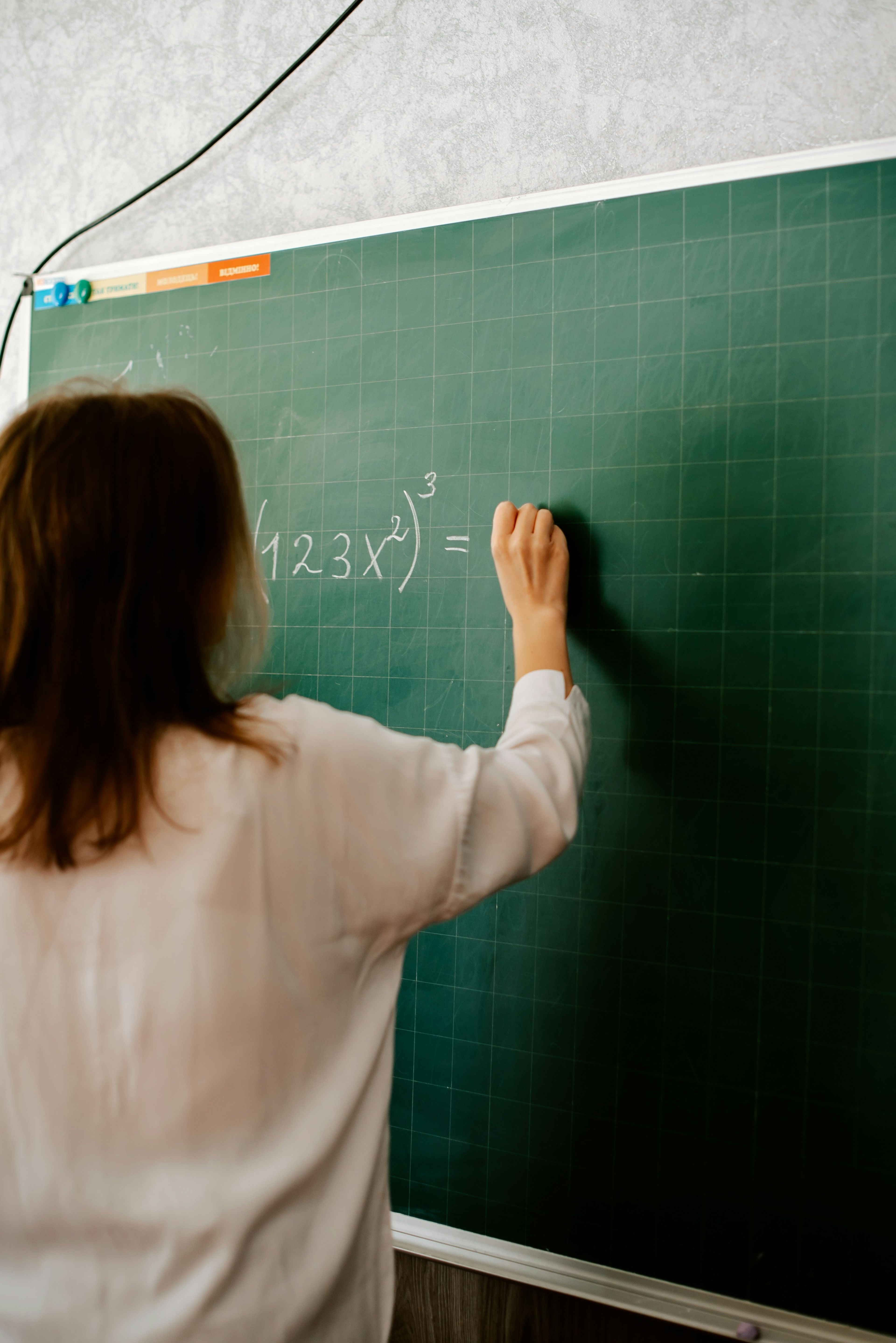 Lærer skriver potensuttrykk på tavla i undervisning i matematikk S1.