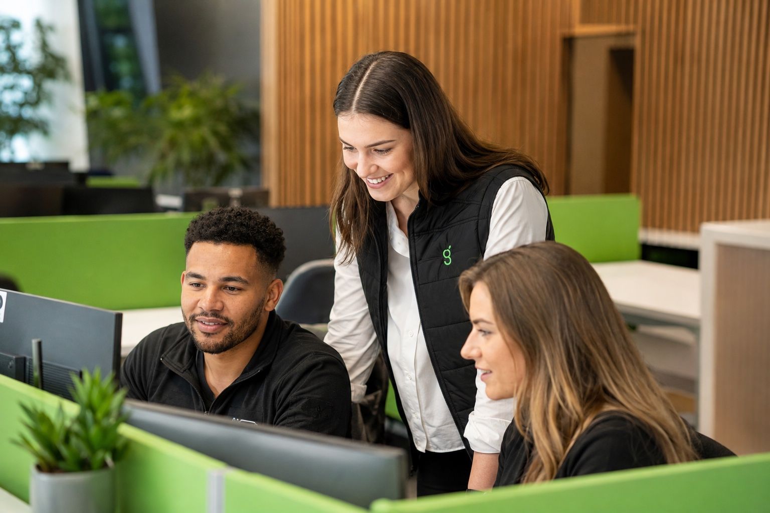 Three Greenarc colleagues collaborating around a computer in the Padiham office