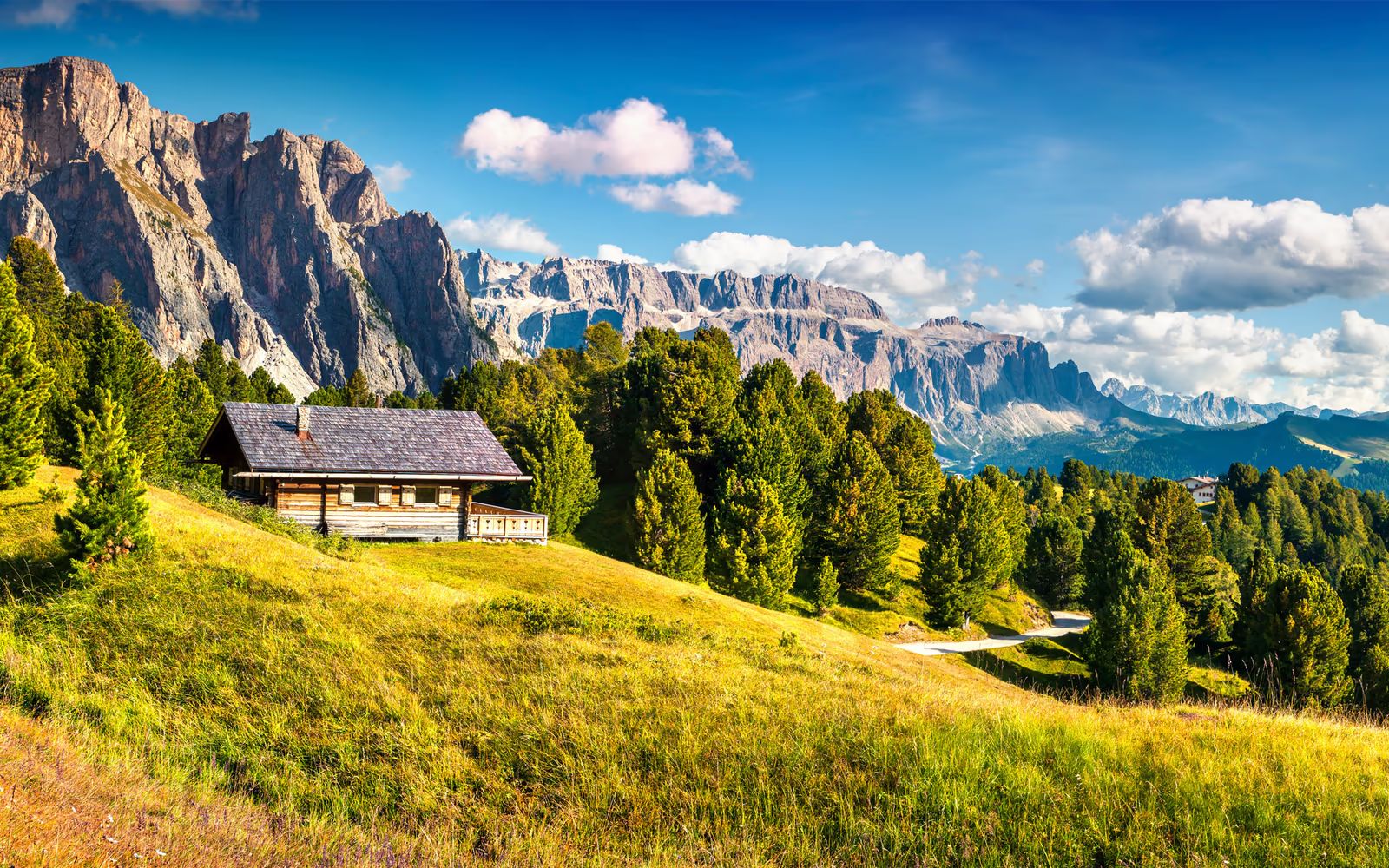 Almhütte auf grüner Wiese vor den Dolomiten