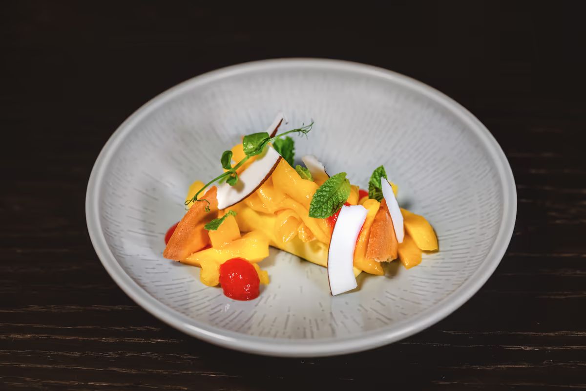 Dessert mit Mangocreme, Kokoschips und Minze