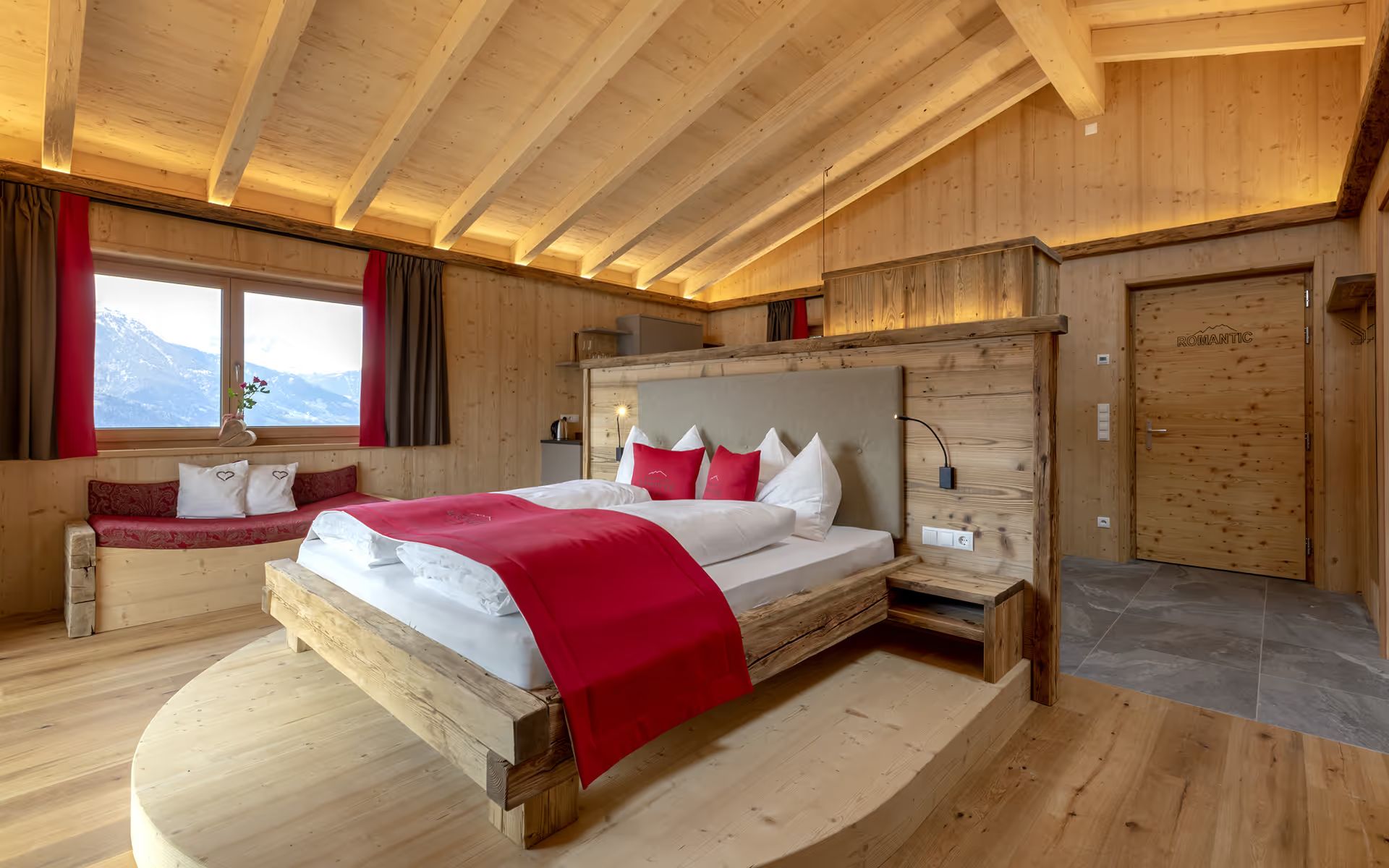 Chalet-Schlafzimmer aus Altholz mit Fenster zu den Bergen