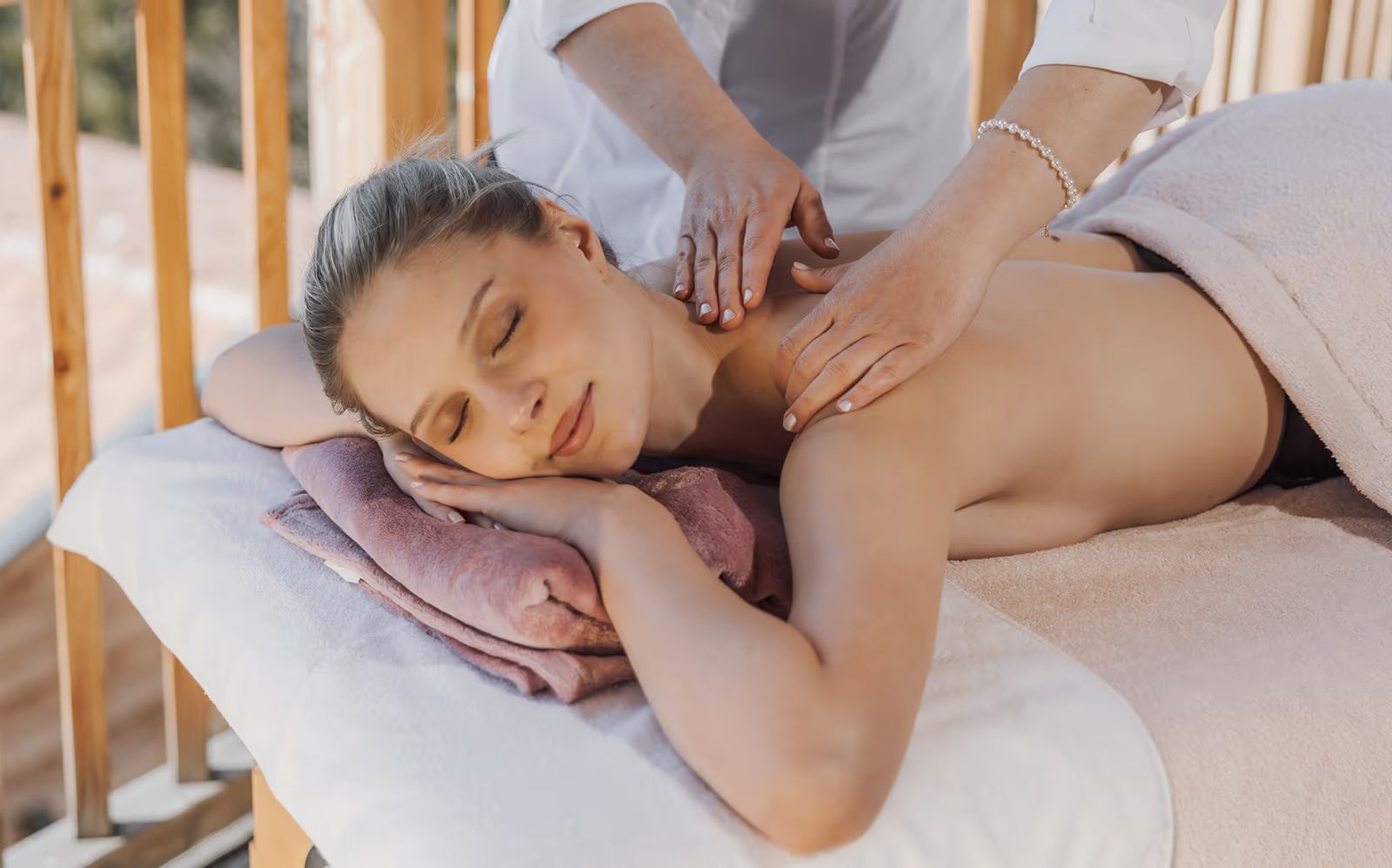 Rückenmassage auf der Liege vor der Holzbrüstung der Terrasse