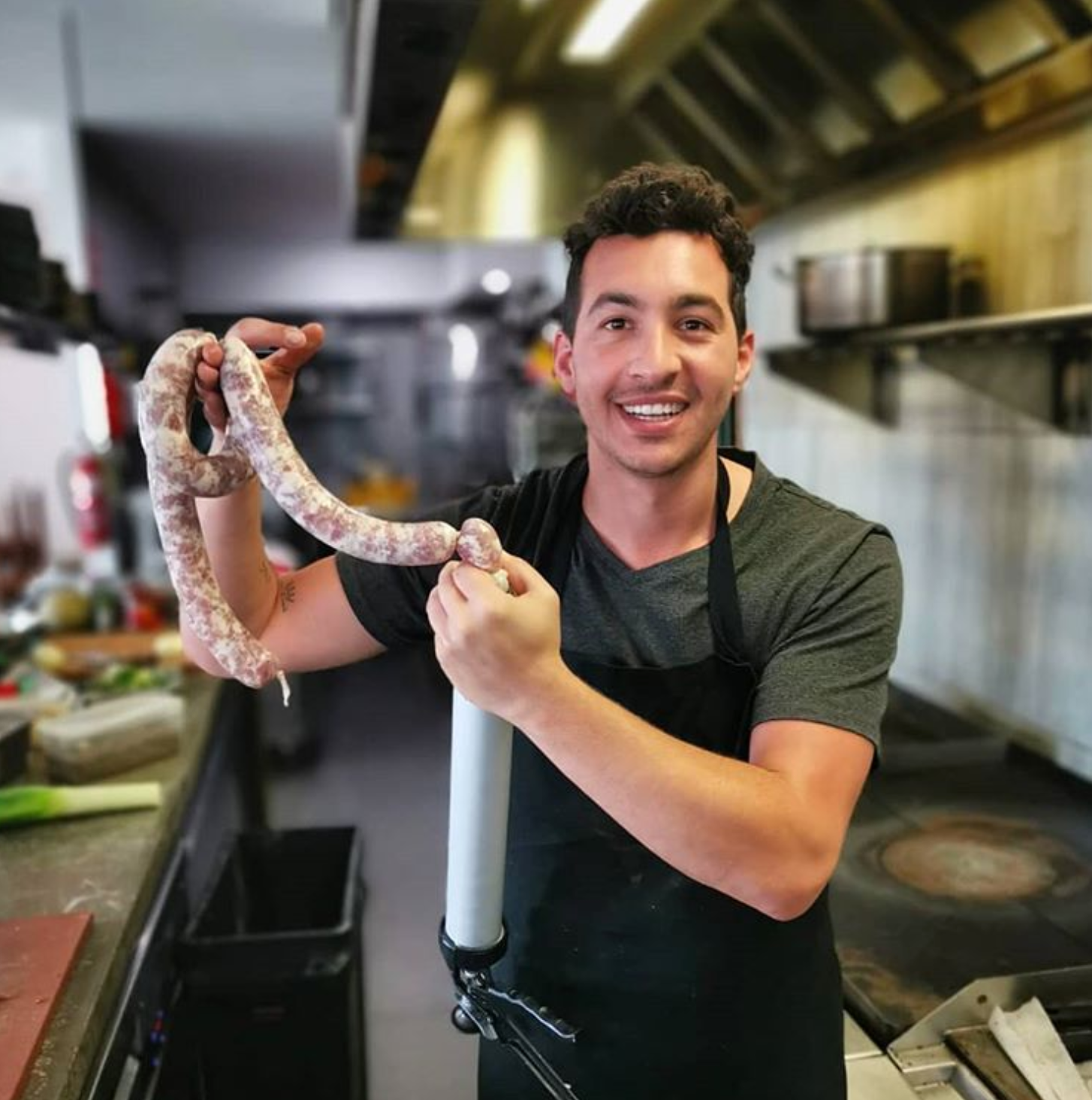 Gabriel of Ziggy's Wildfoods holding portion of cured sausage