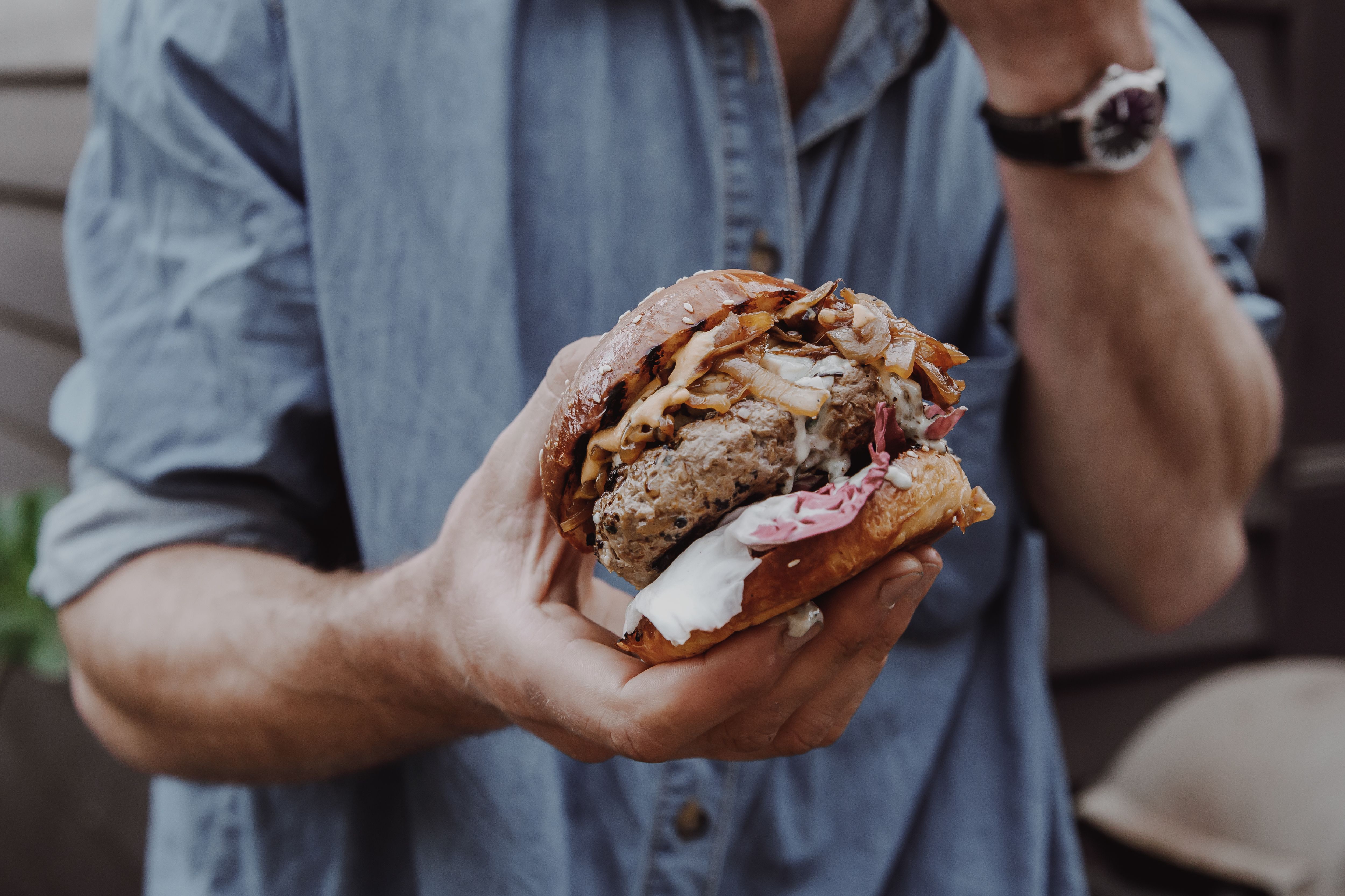 Hands holding wild venison burger with radicchio and blue cheese