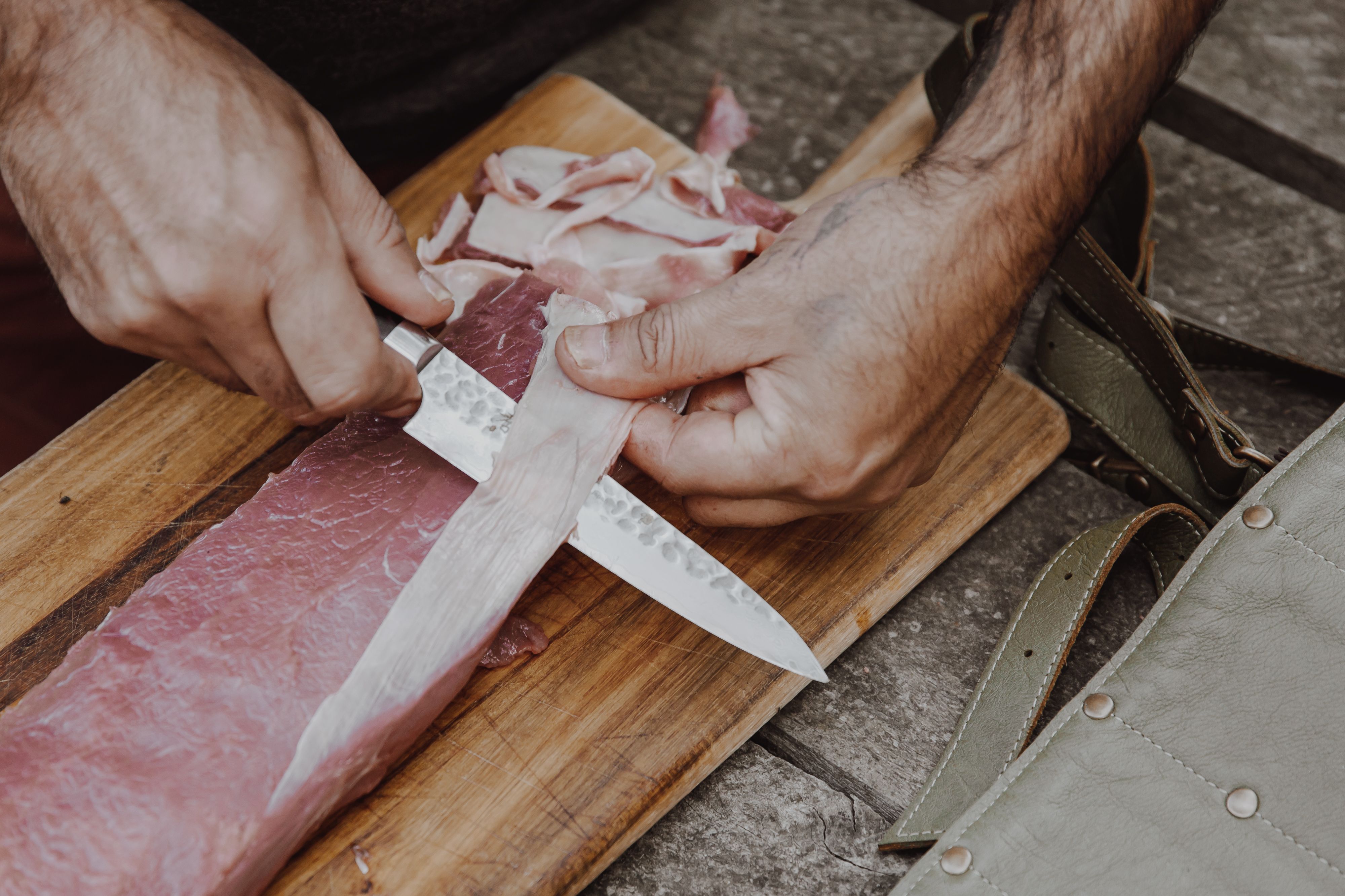 Chef clayton donovan trimming a wild venison backstrap on wooden board